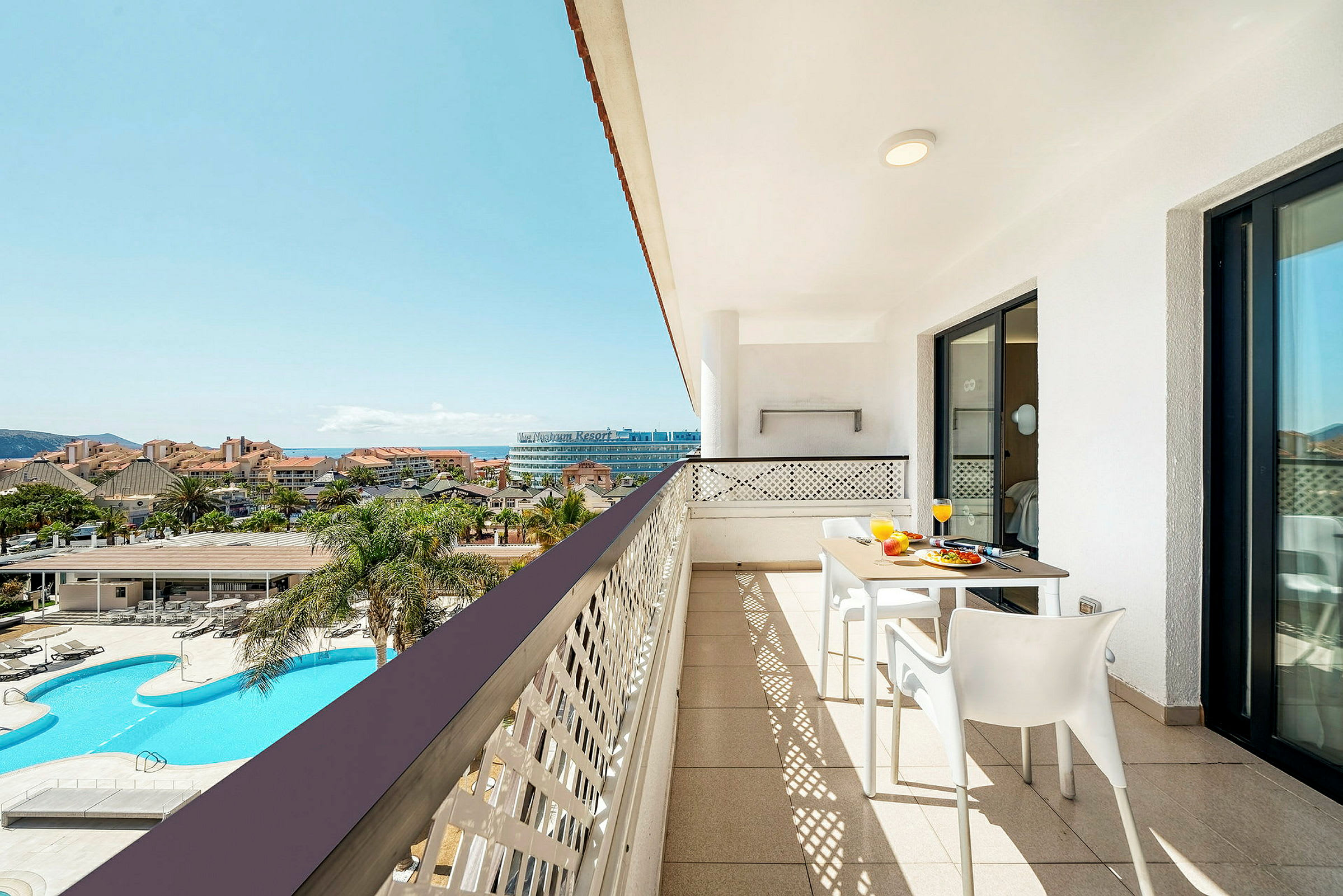En balkong med utsikt över ett poolområde och en resort. (AI-genererad text)