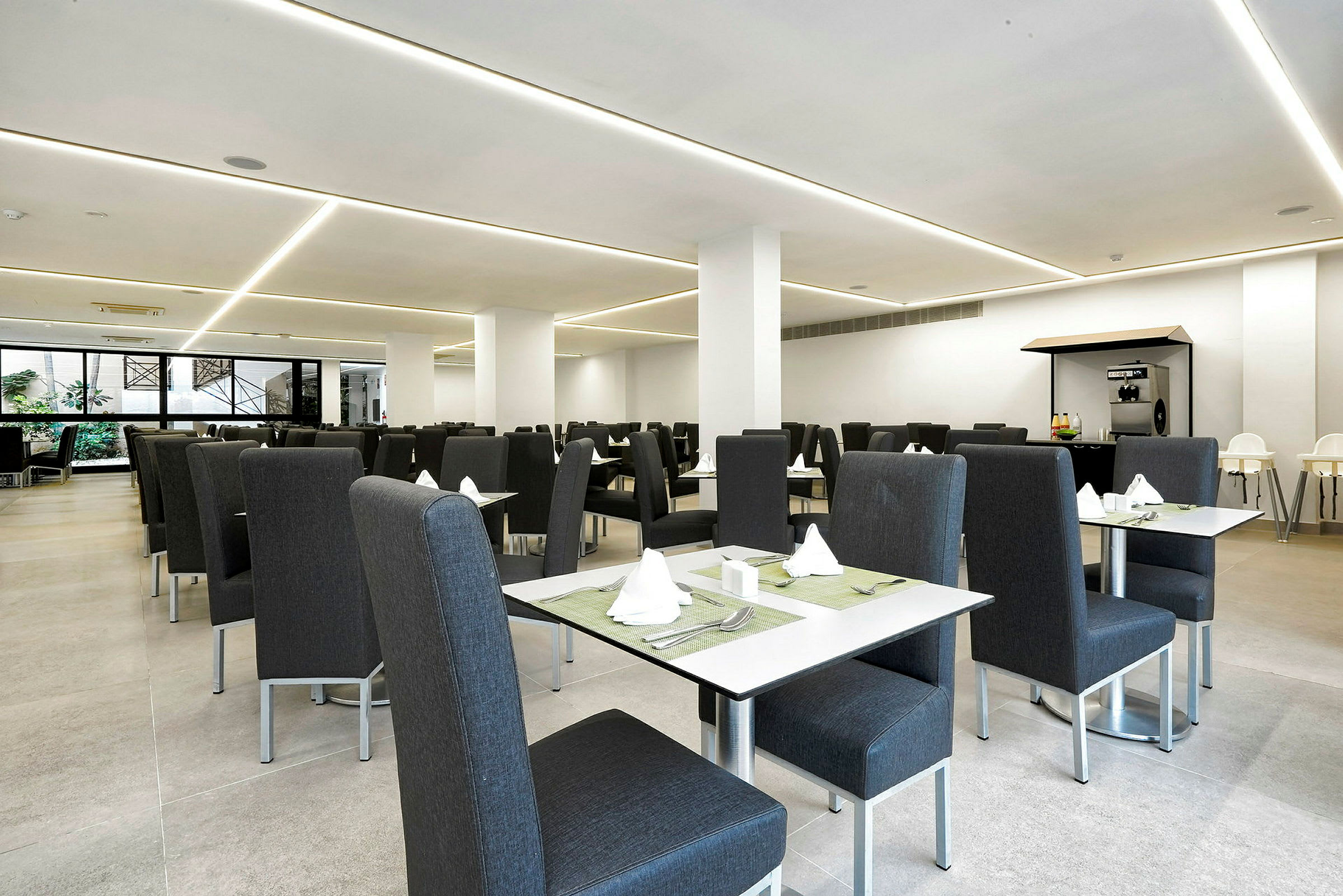 Ett modernt restaurangområde med grå stolar och dukade bord. (AI-genererad text)