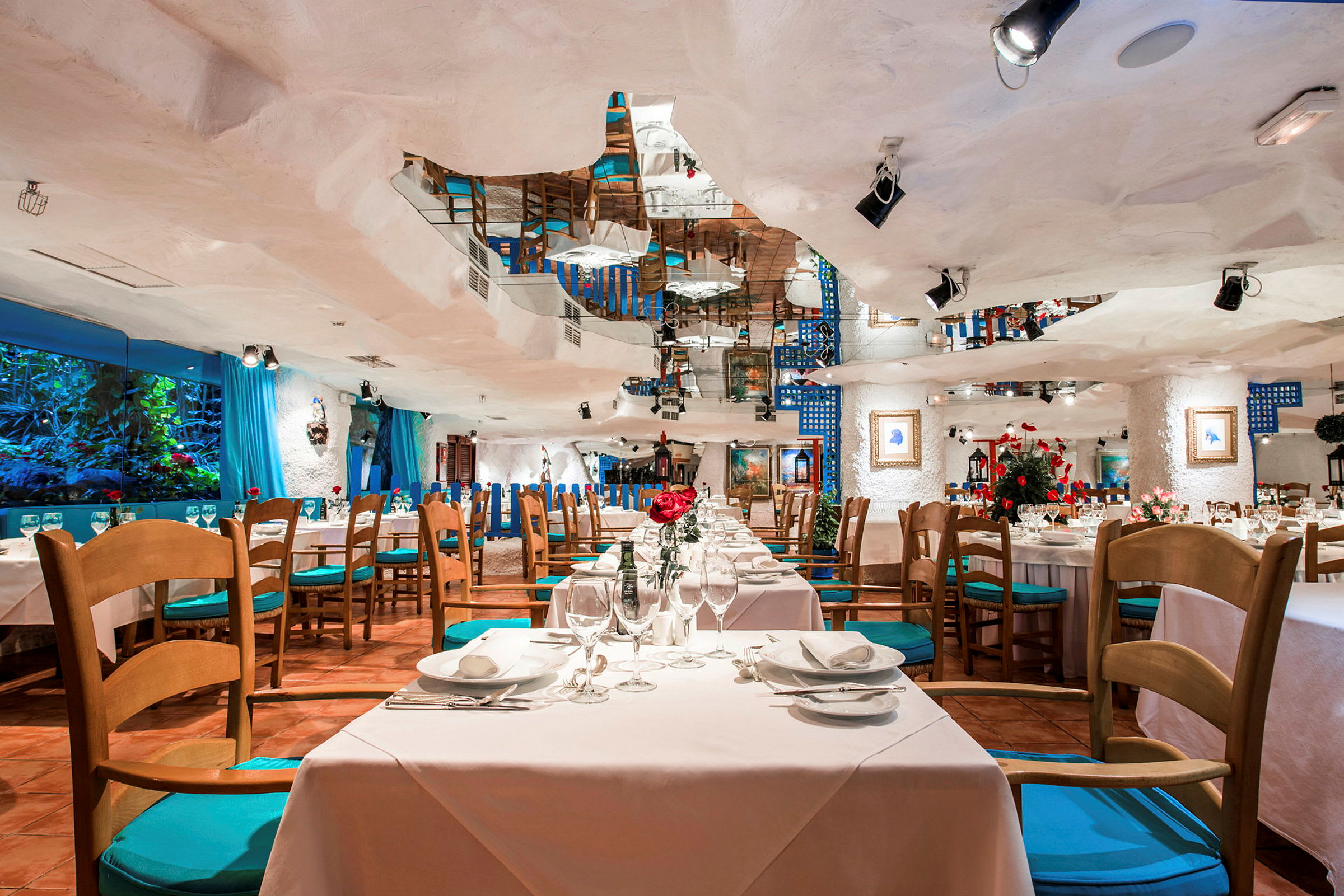Interiören av en restaurang med bord och stolar, dekorerad med blommor och speglar. (AI-genererad text)