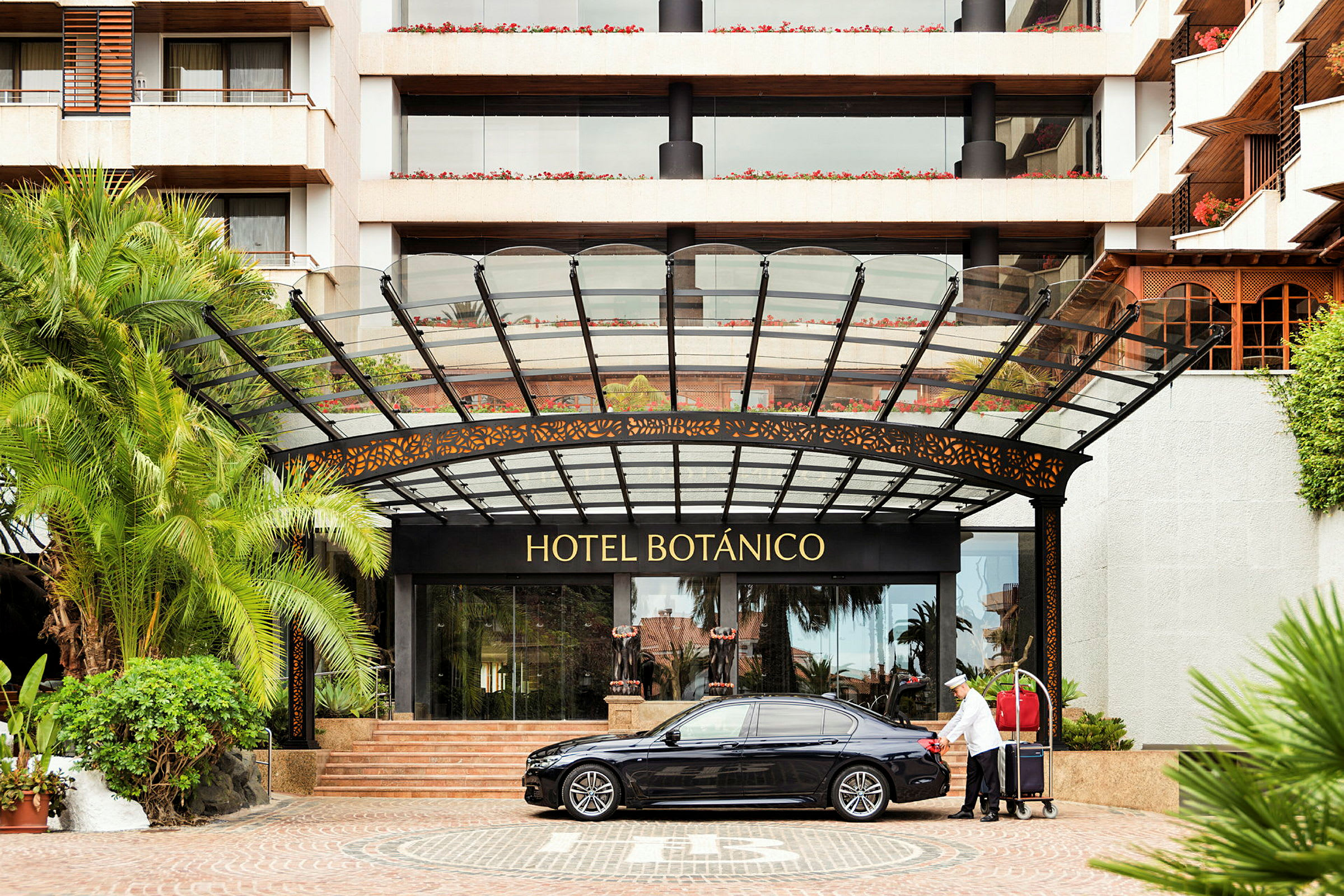 Entrén till Hotel Botánico med en bil och en bagagevagn. (AI-genererad text)