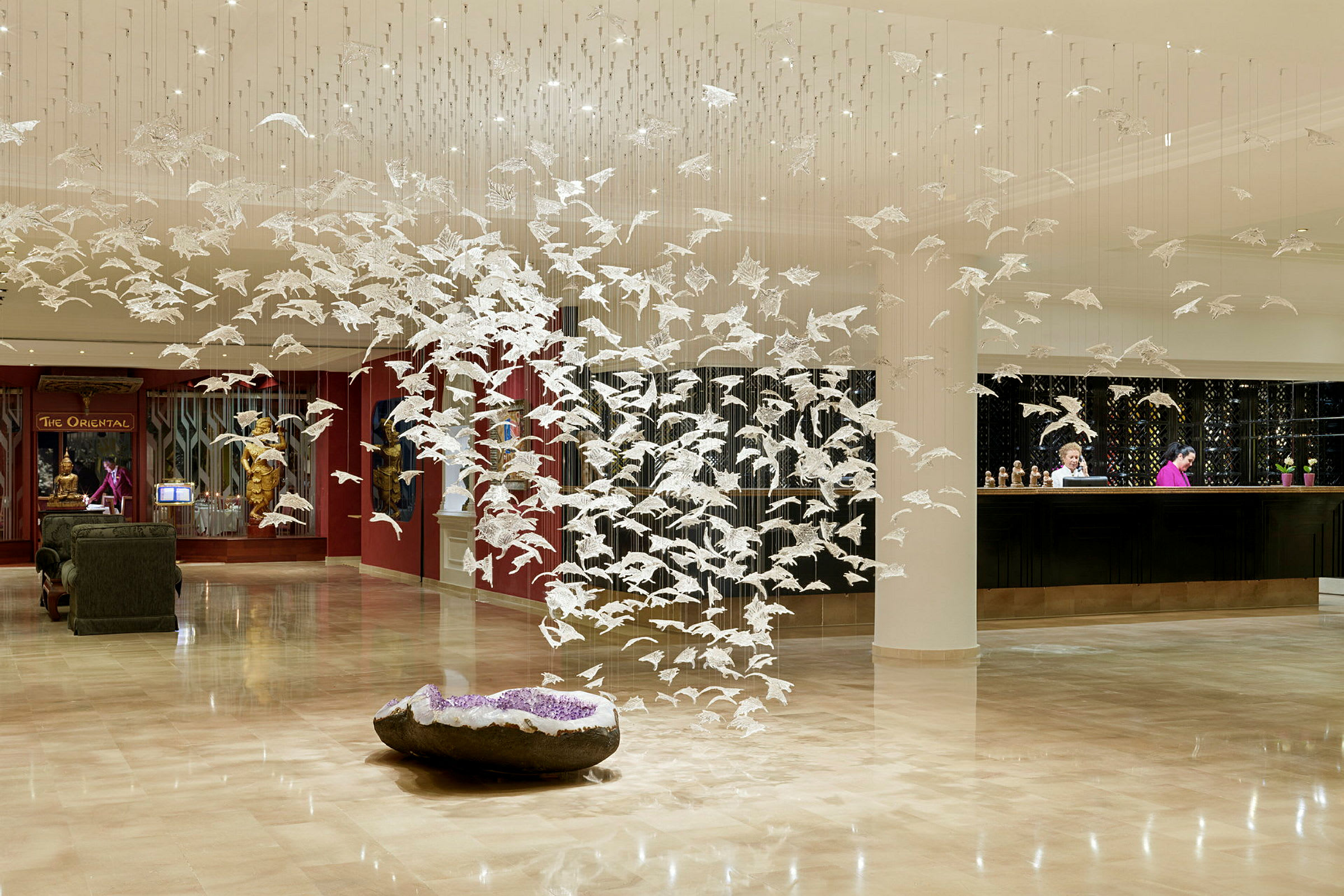 Lobby med modern konstinstallation av vita fåglar i hängande formation. (AI-genererad text)