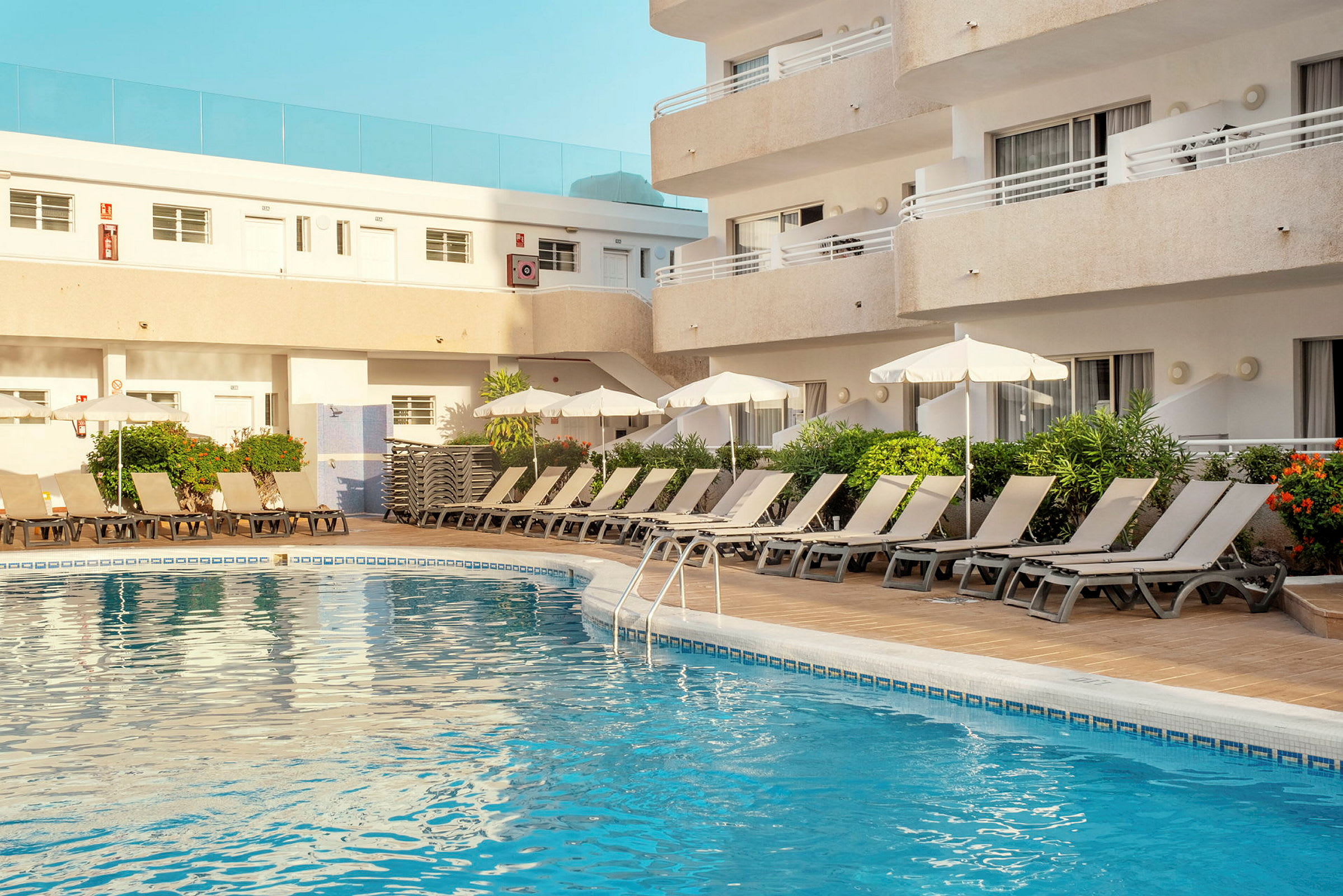 Utomhuspool med solstolar och parasoller vid ett hotell. (AI-genererad text)