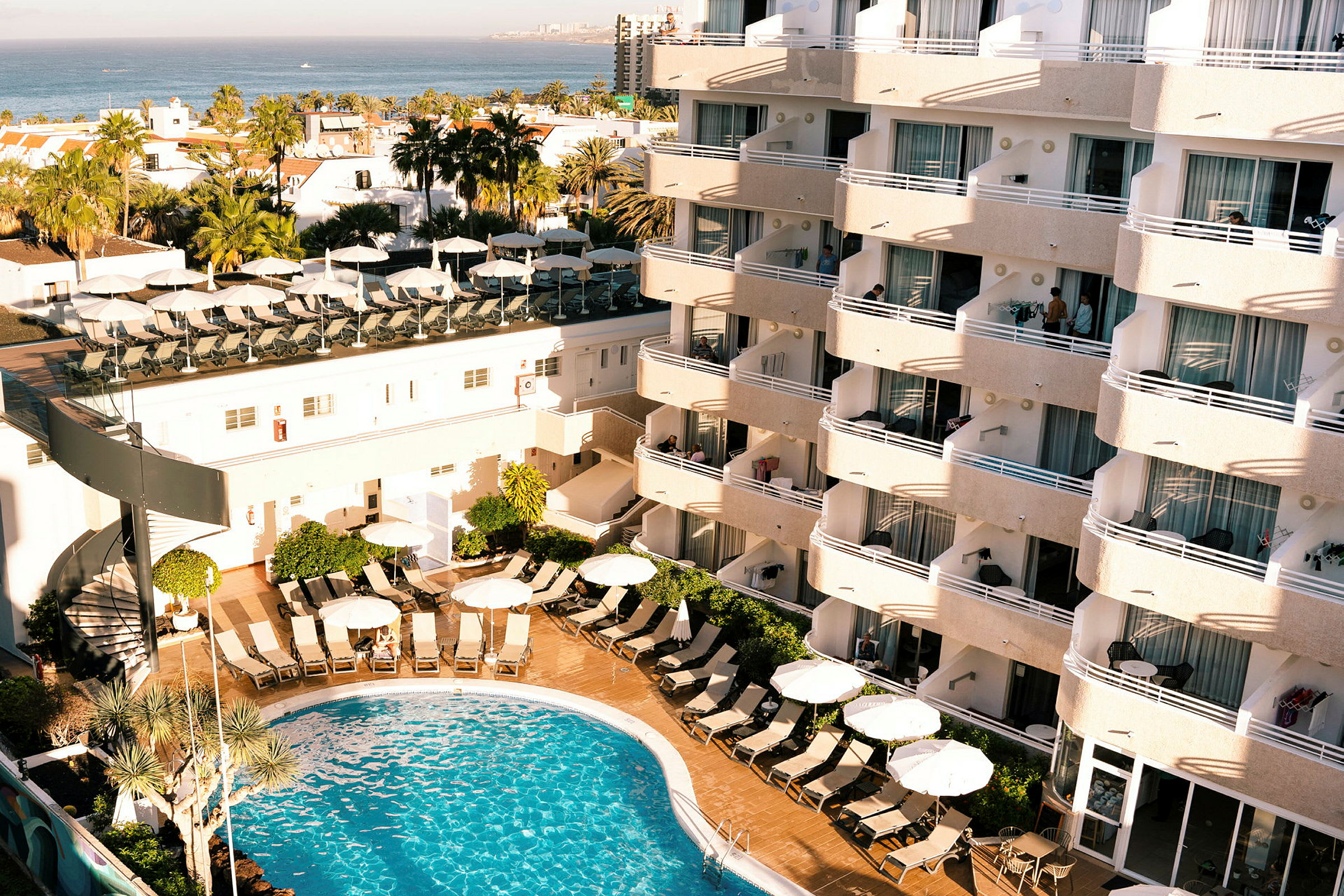 Hotellbyggnad med balkonger och en pool i förgrunden. (AI-genererad text)
