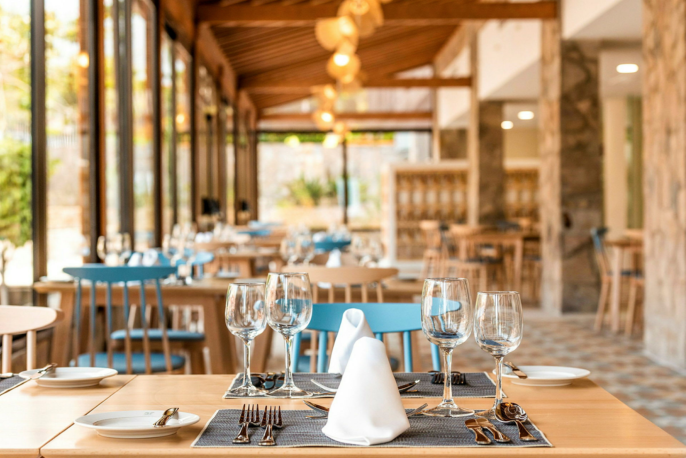 En elegant restaurang med träinredning, dukade bord och blå stolar. (AI-genererad text)