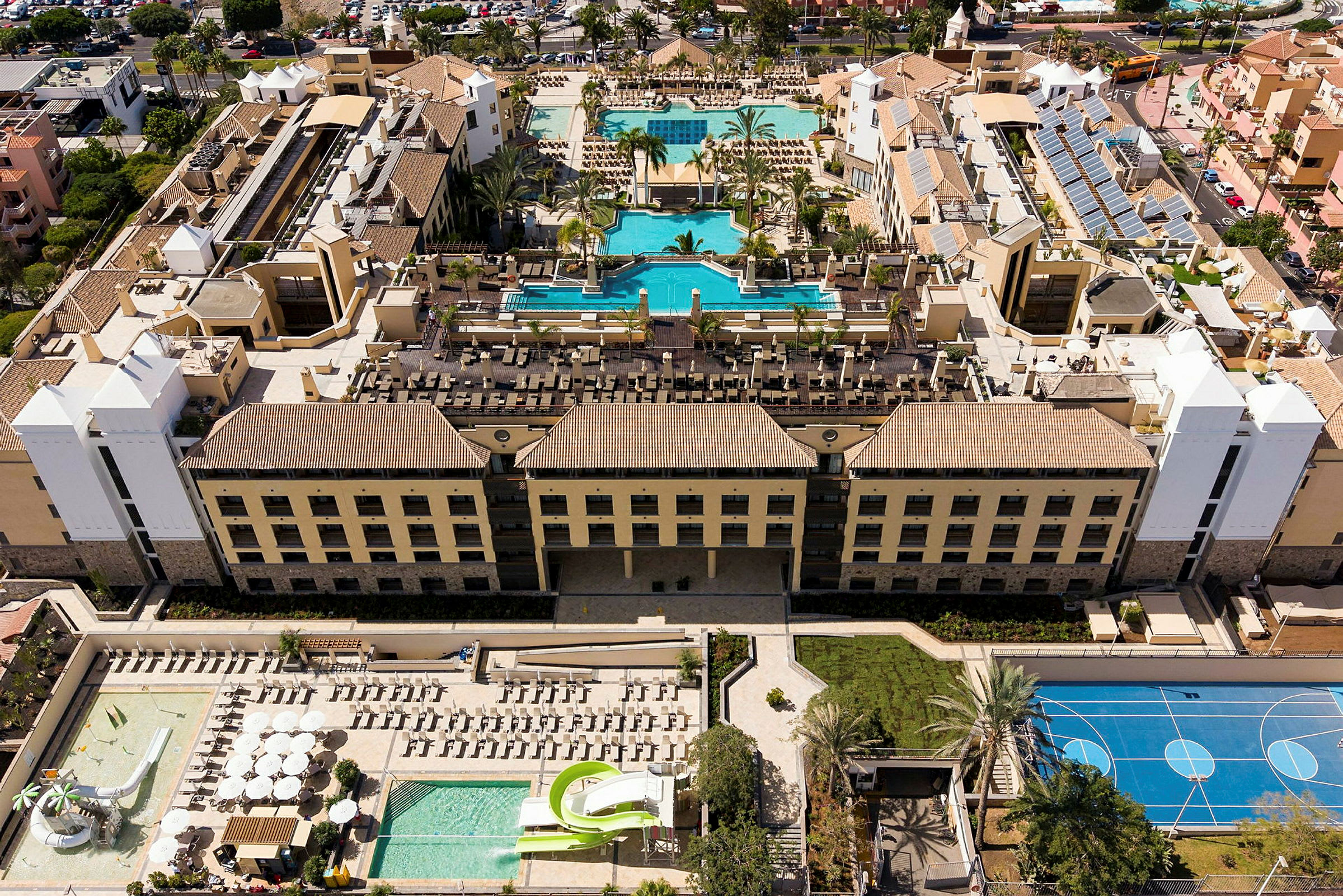 Flygfoto av en semesterdestination med hotellbyggnader och poolområden. (AI-genererad text)