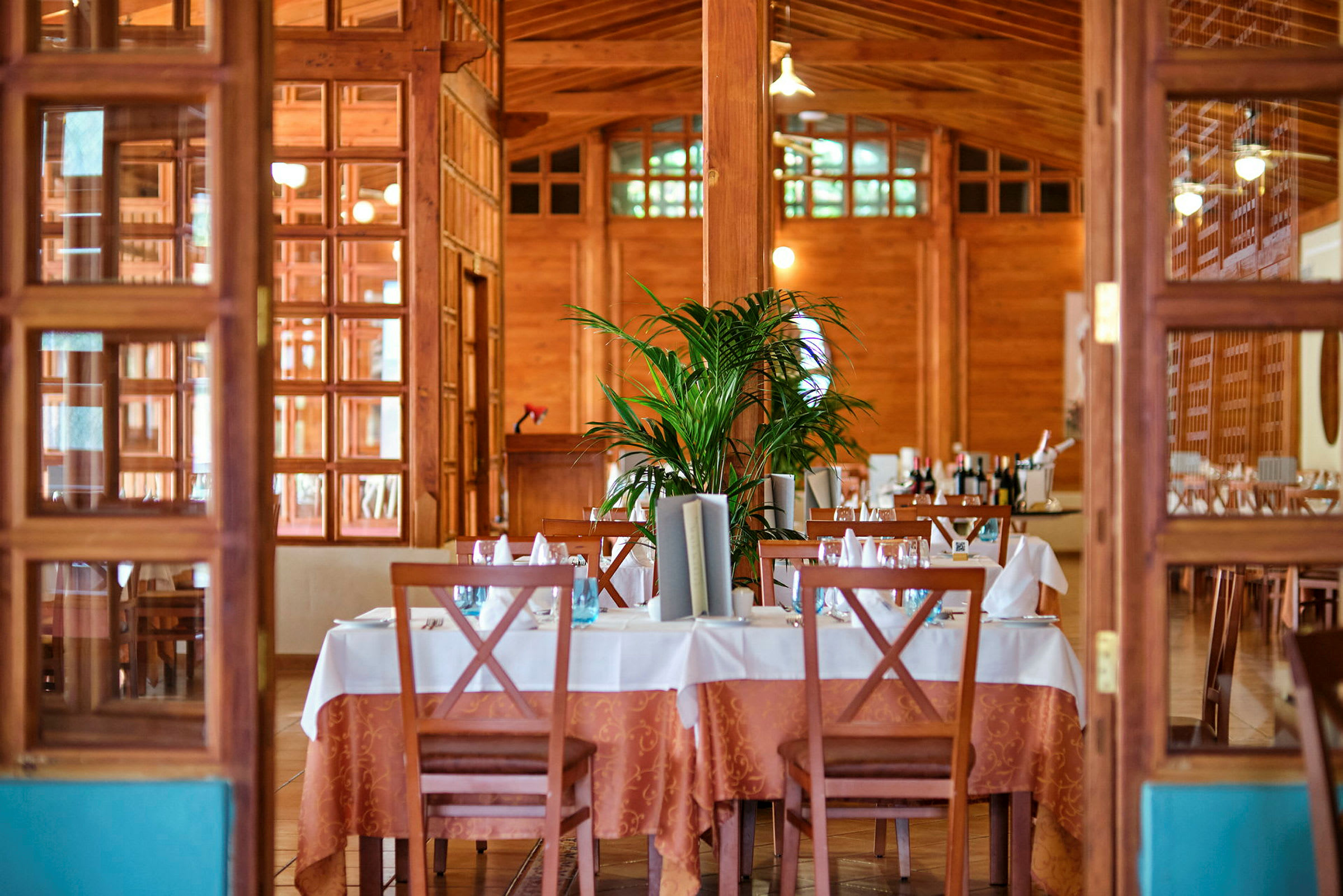 En elegant restaurang med dukade bord, dekorerade stolar och en inredning av trä. (AI-genererad text)