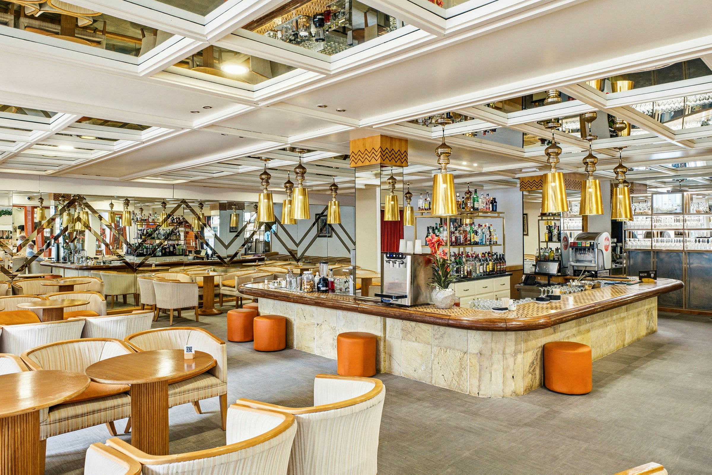 Ett elegant hotellbarområde med sittgrupper, en lång bardisk och moderna designlampor. (AI-genererad text)