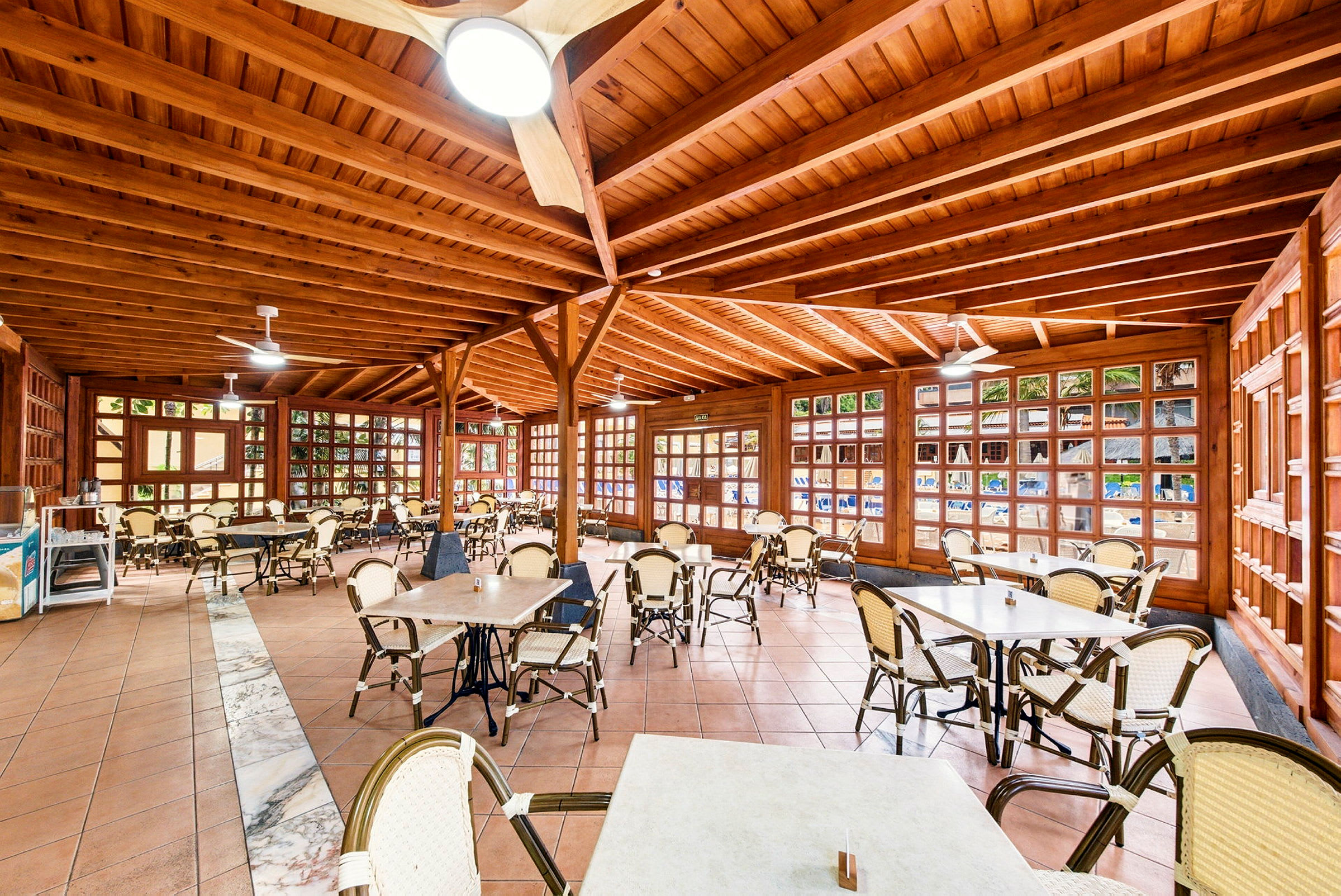 En restaurang med träinredning, bord och stolar utspridda över golvet. (AI-genererad text)