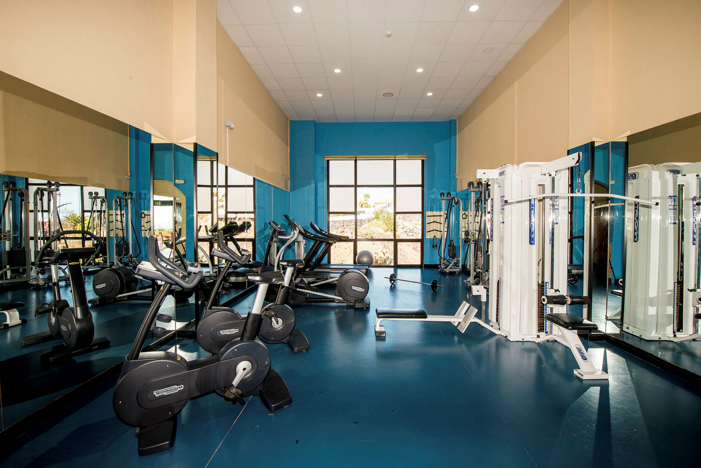 Bild av ett gym med träningsutrustning inklusive motionscyklar, löpband och styrketräningsmaskiner. (AI-genererad text)