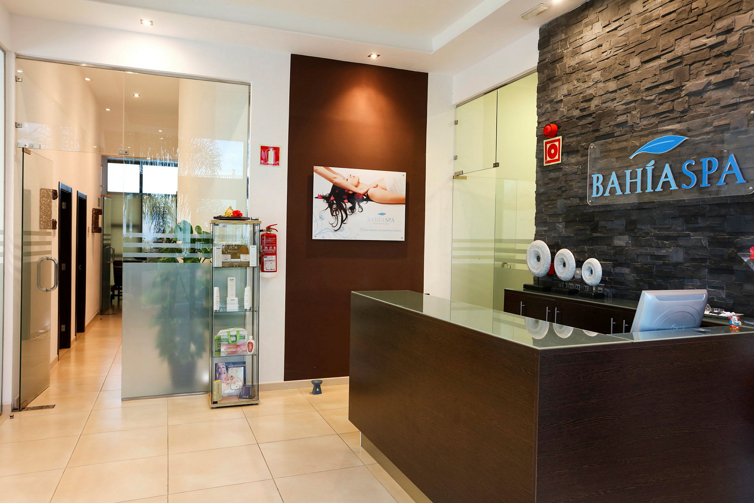 Receptionen på Bahía Spa med glas- och träinredning. (AI-genererad text)