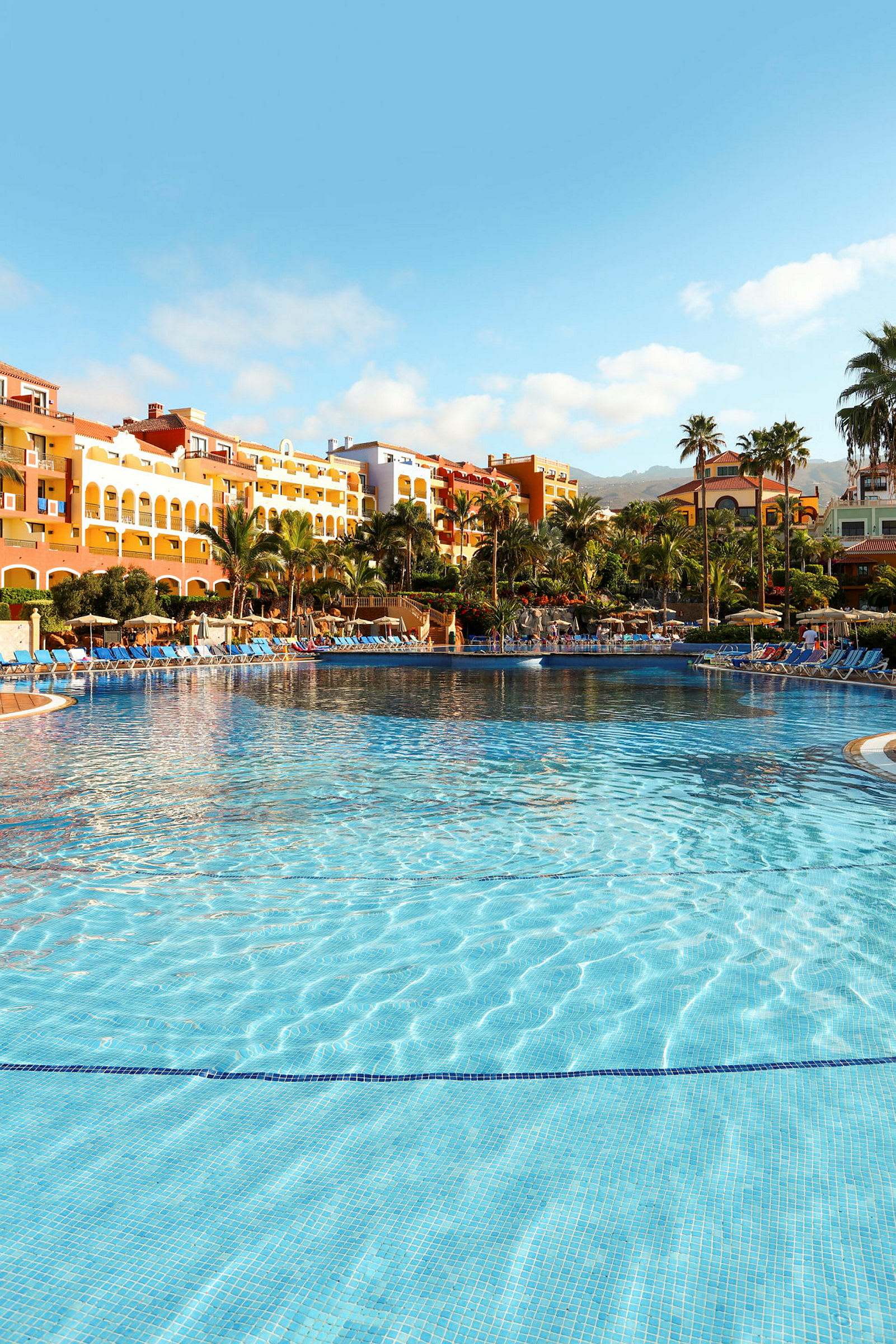 Pool med klart vatten och hotellbyggnader i bakgrunden. (AI-genererad text)