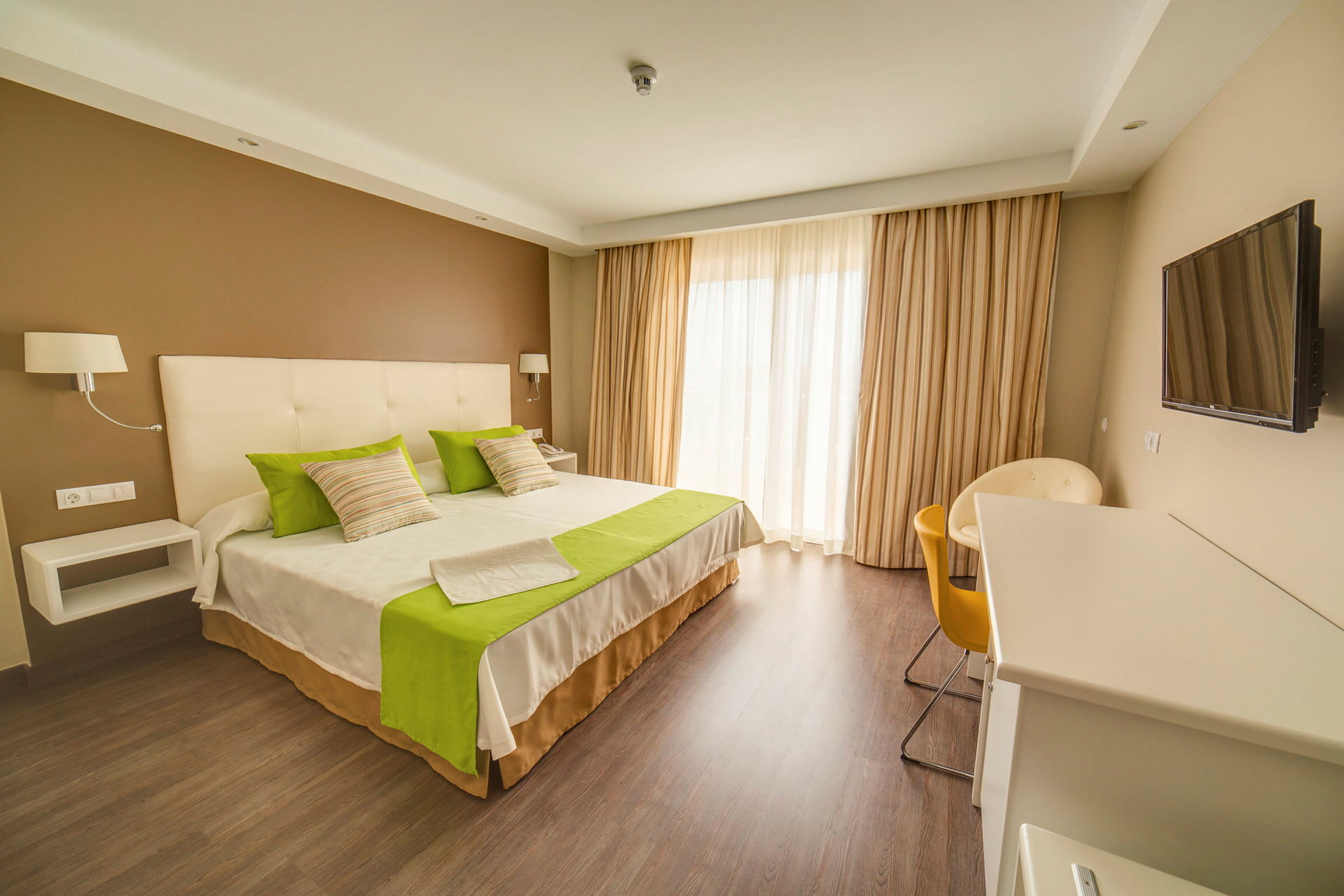 Hotellrum med dubbelsäng, gröndetaljer och modern inredning. (AI-genererad text)