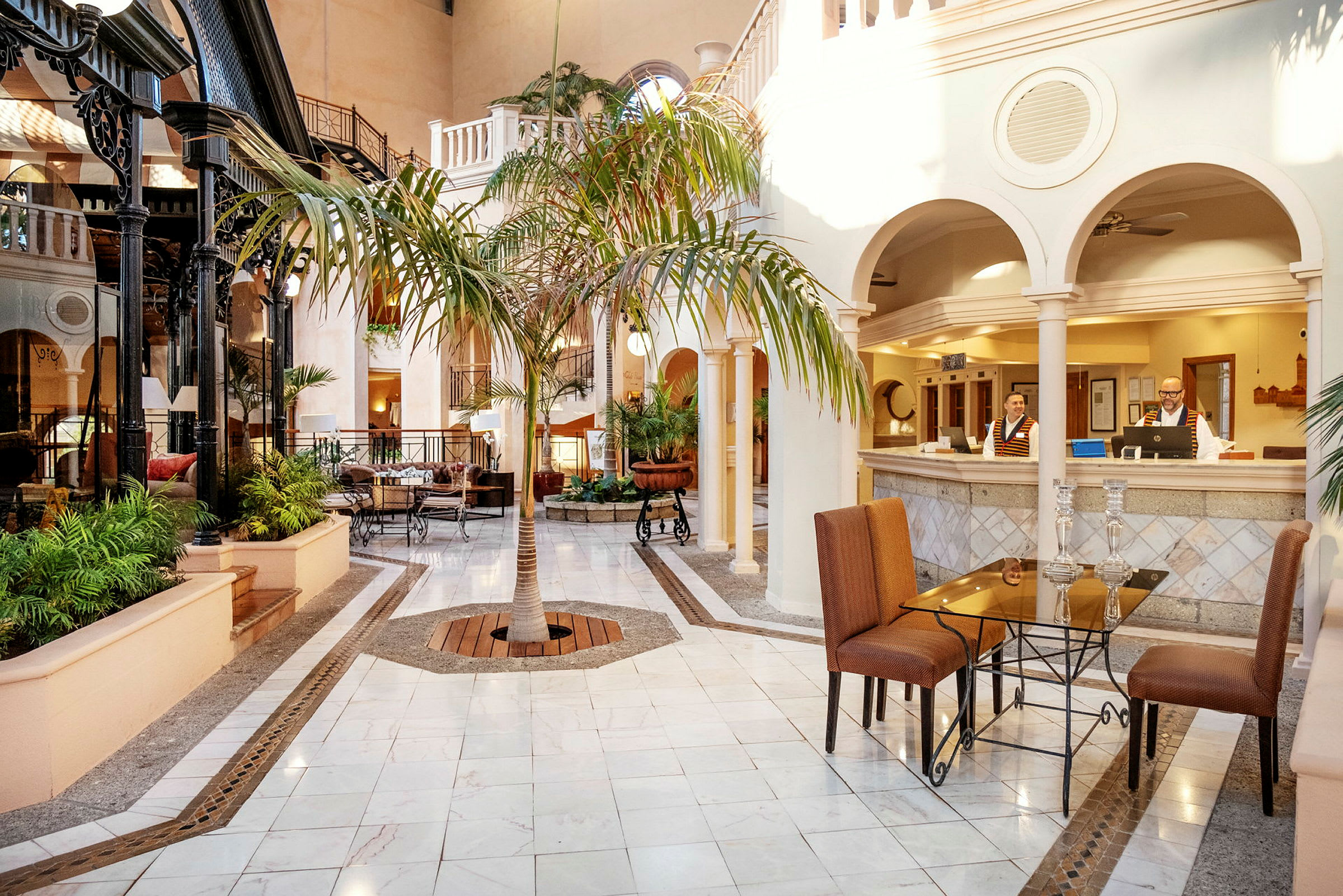 Hotellets lobby med marmorbelagt golv, sittgrupper och en central palm. (AI-genererad text)