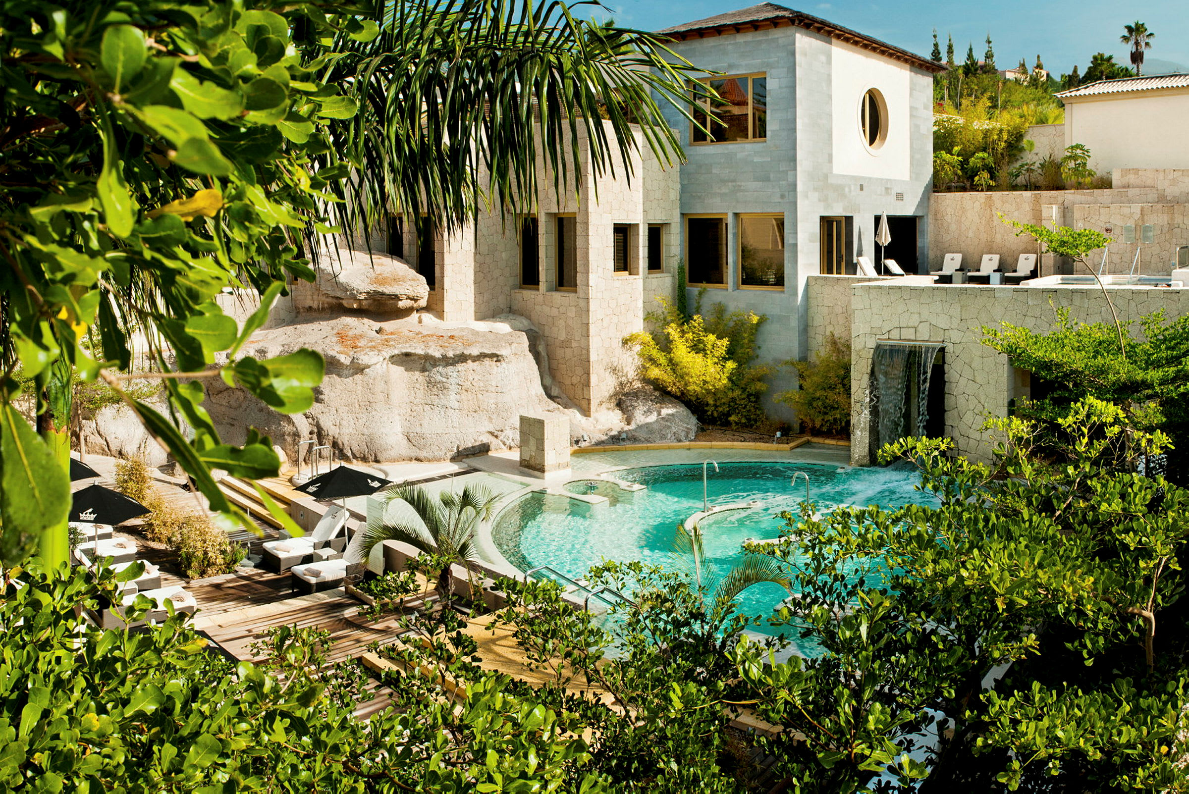Bild av en stenbyggnad med pool och grönska. (AI-genererad text)