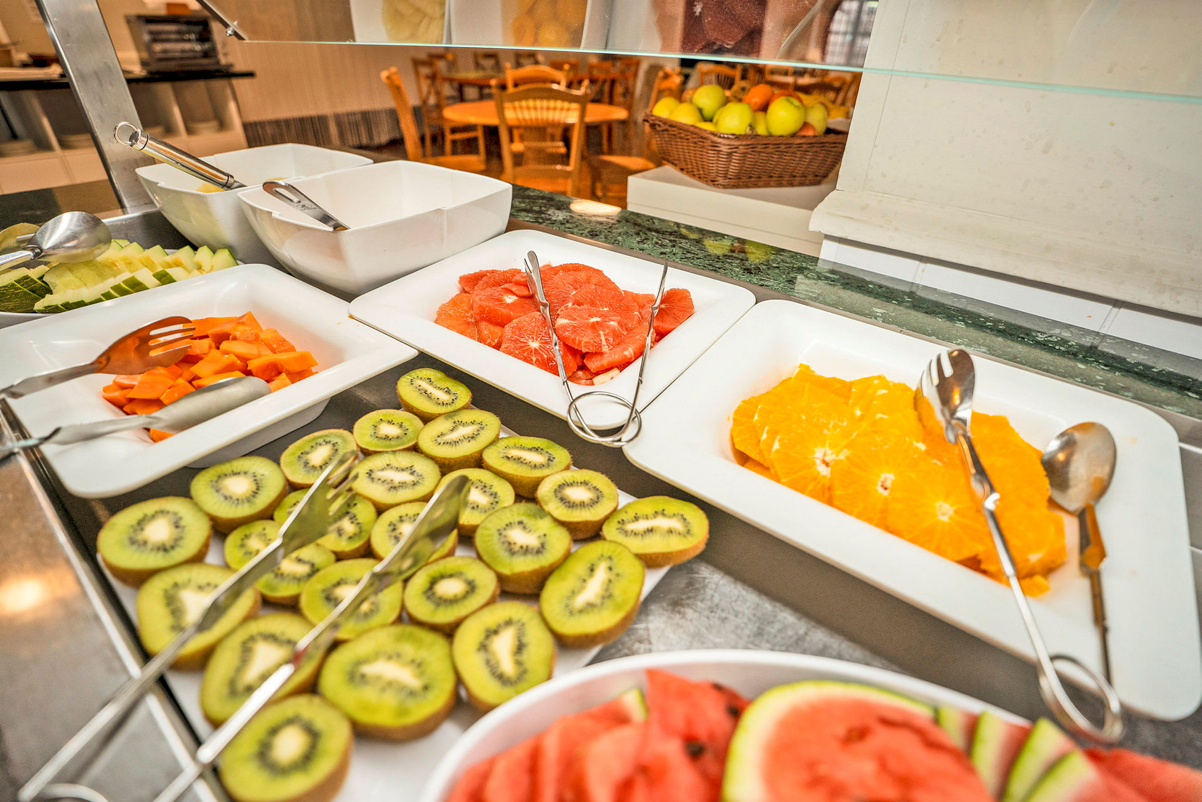 Buffébord med skivad frukt som apelsiner, kiwi, och vattenmelon i fat. (AI-genererad text)