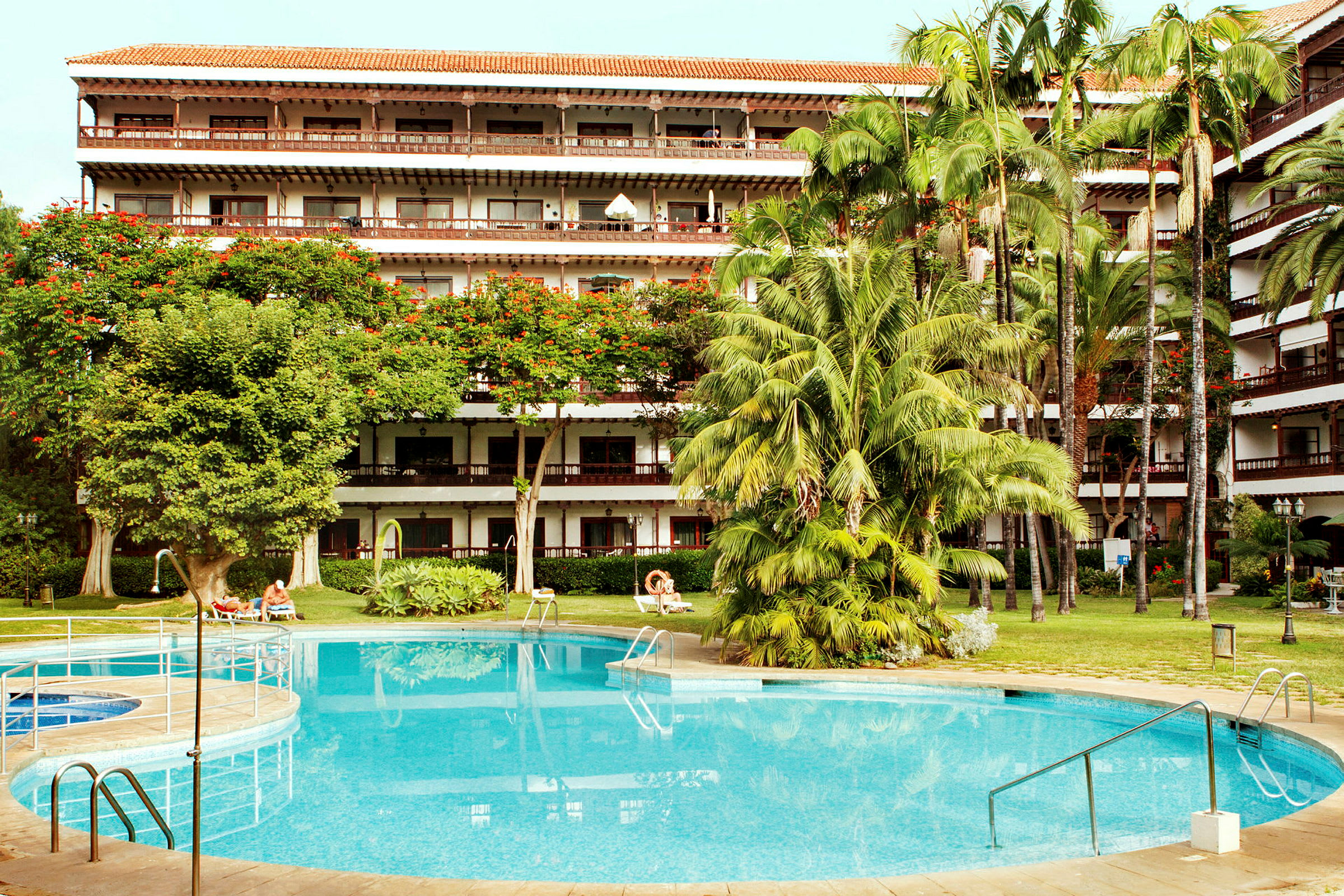 Hotell med grönskande trädgård och pool. (AI-genererad text)