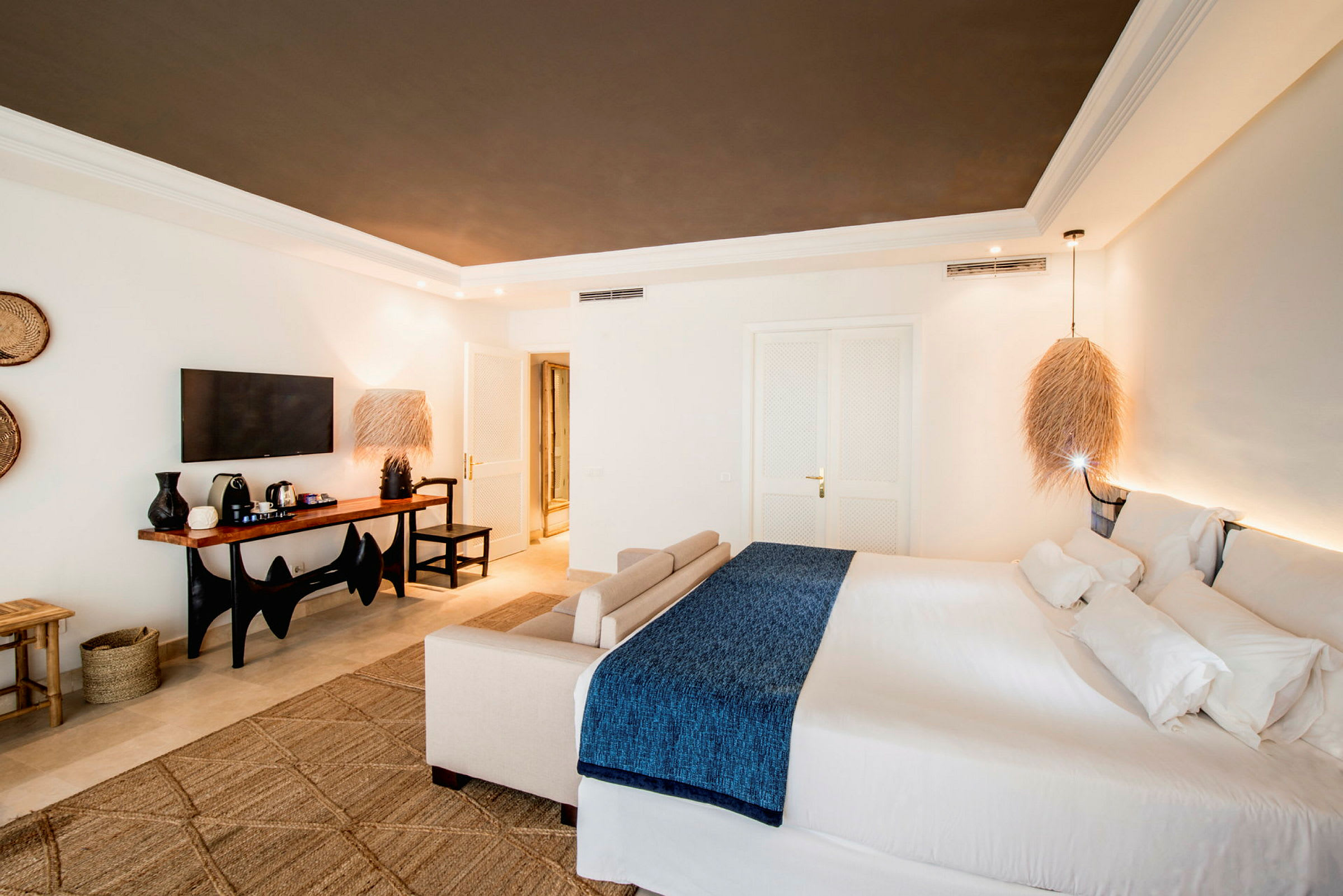 Ett modernt hotellrum med en stor säng och en sittgrupp, samt en TV och ett bord med kaffebryggare. (AI-genererad text)