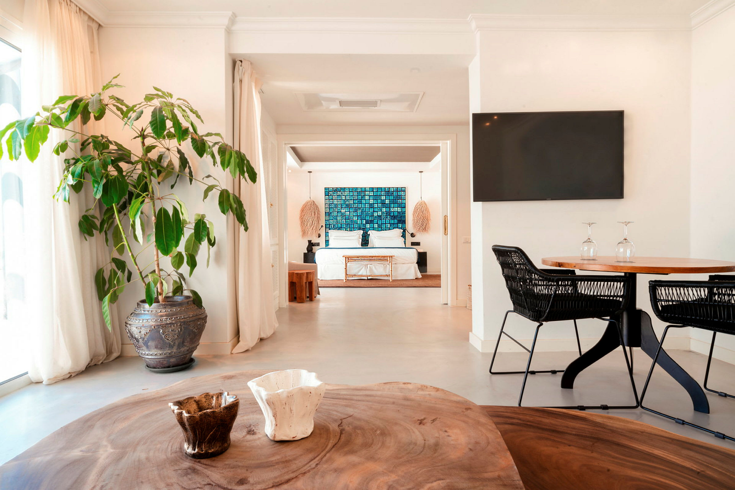 Ett ljust och modernt hotellrum med en stor säng, dekorerad med blå konst på väggen och omgiven av eleganta möbler. (AI-genererad text)