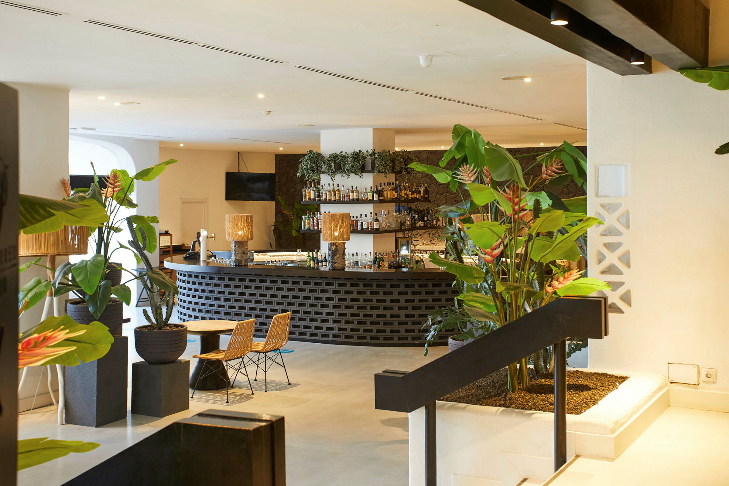 En hotellbar med växtdekorationer, sittplatser och upplyst inredning. (AI-genererad text)