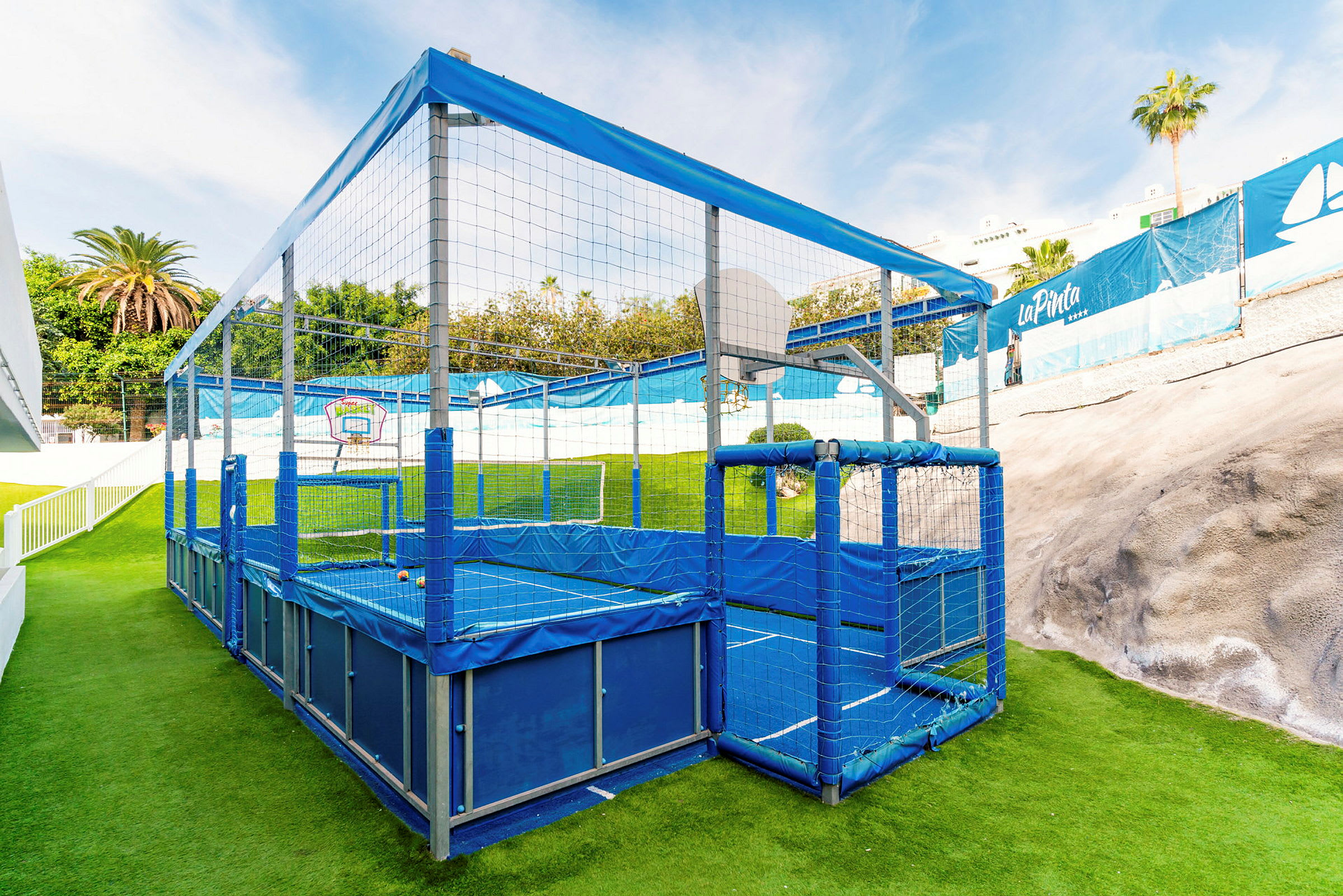 Inhägnad sportlekplats med konstgräs och basketkorg. (AI-genererad text)
