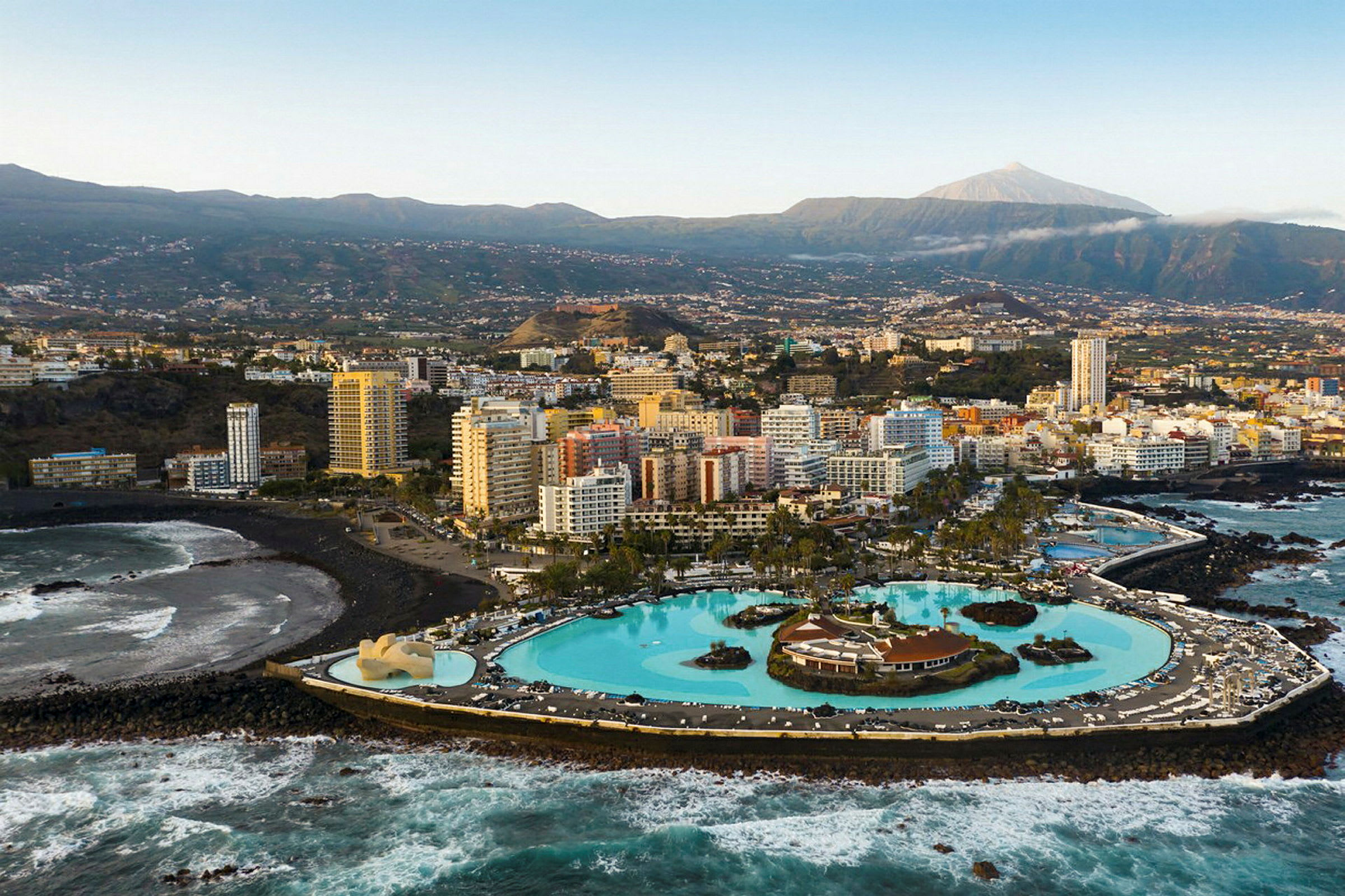 Stadsbild med moderna byggnader nära en kust och en stor konstgjord pool. (AI-genererad text)