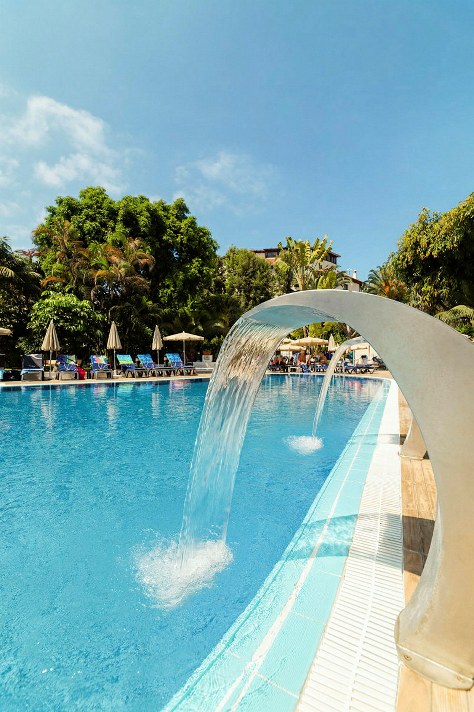 En pool med vattenfall och omgivande grönska. (AI-genererad text)