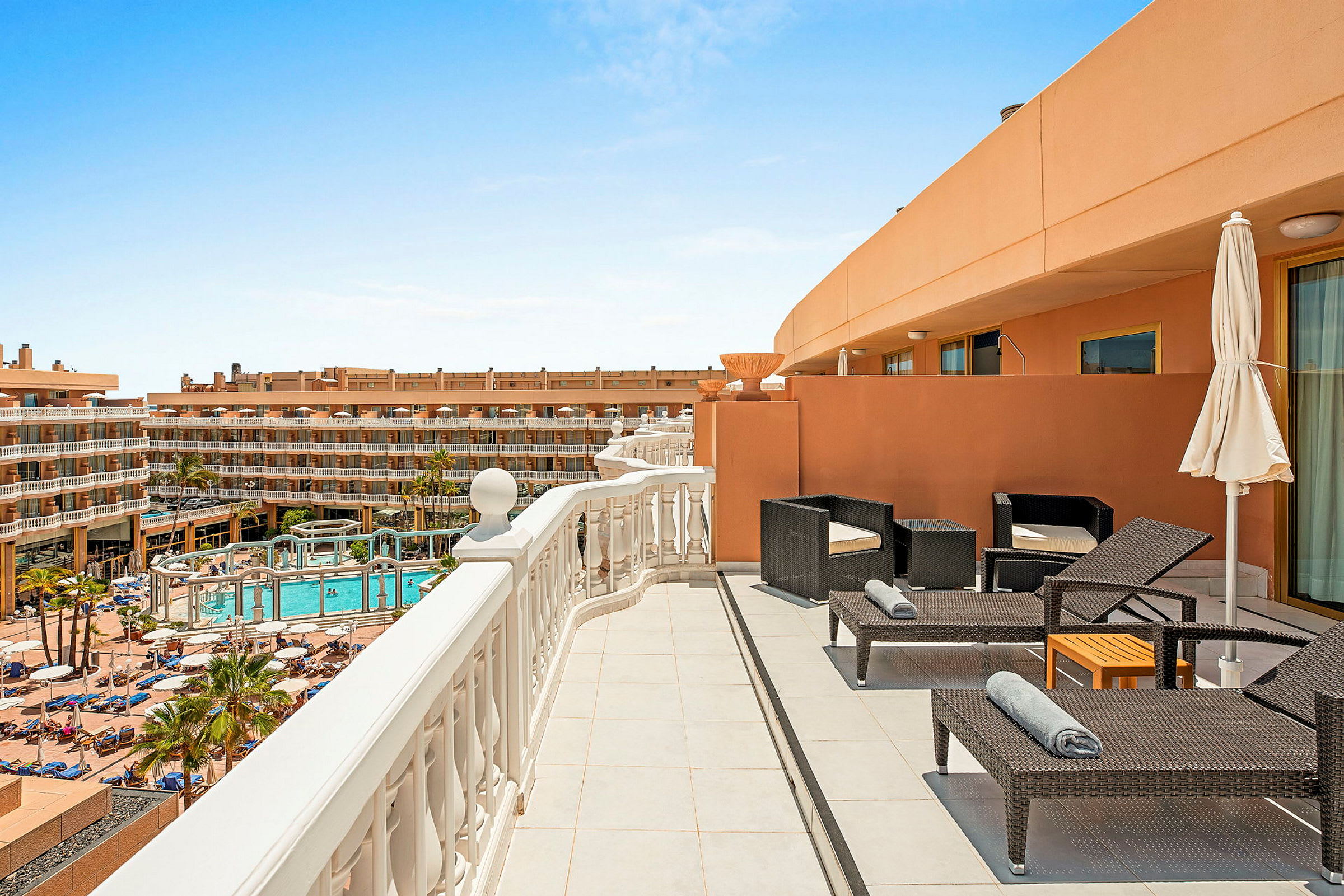 En hotellterrass med stolar, solstolar och utsikt över poolområdet. (AI-genererad text)