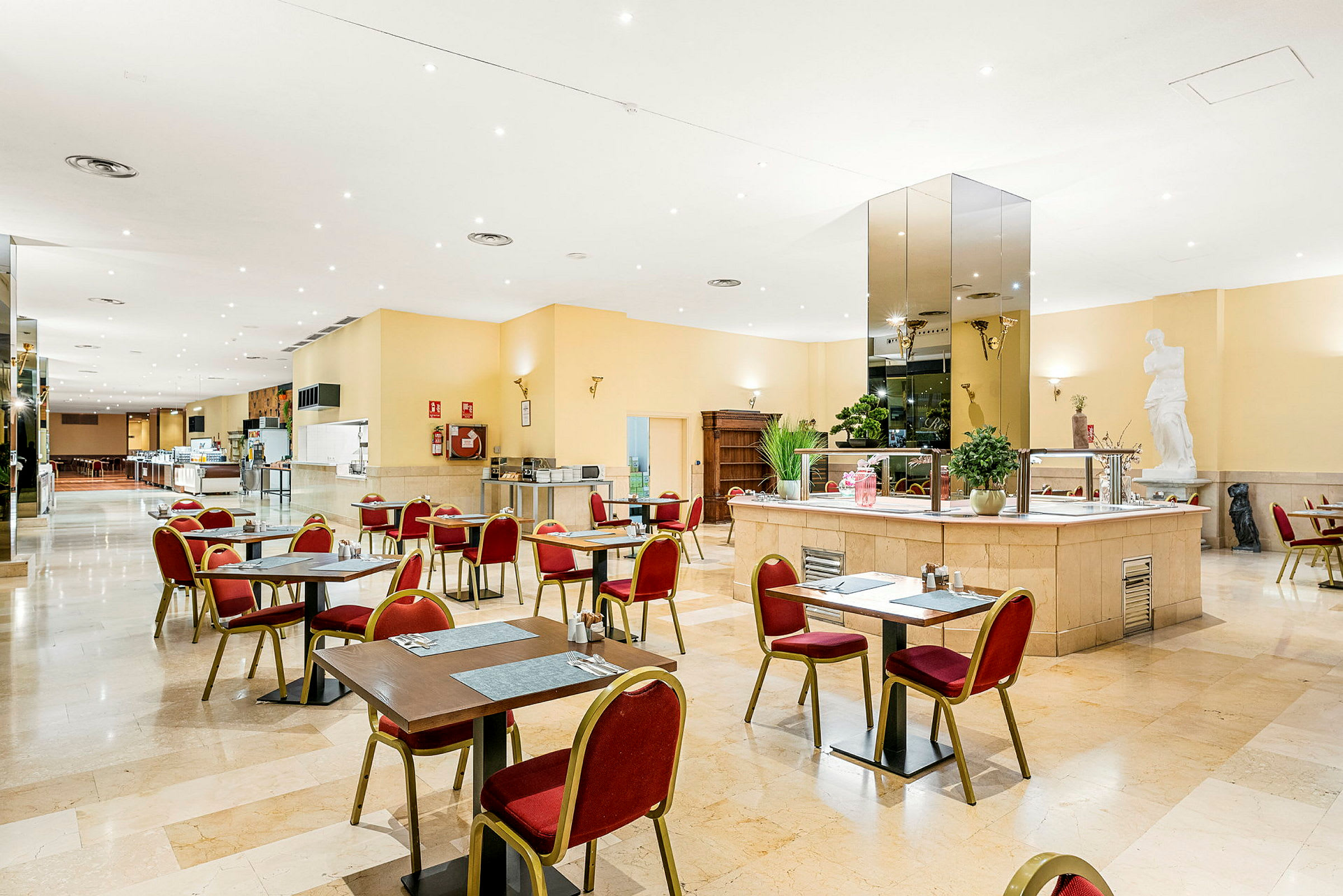 Restaurang med bord och stolar placerade i ett rymligt och ljust inrett utrymme. (AI-genererad text)