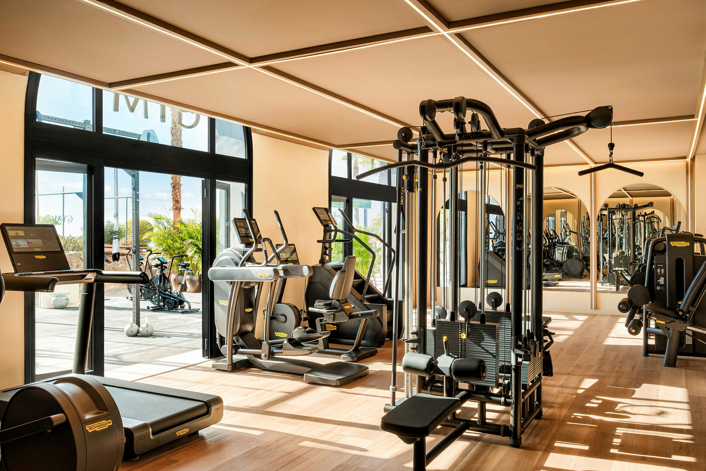 Bild av ett gym med olika träningsmaskiner och fönster som släpper in dagsljus. (AI-genererad text)