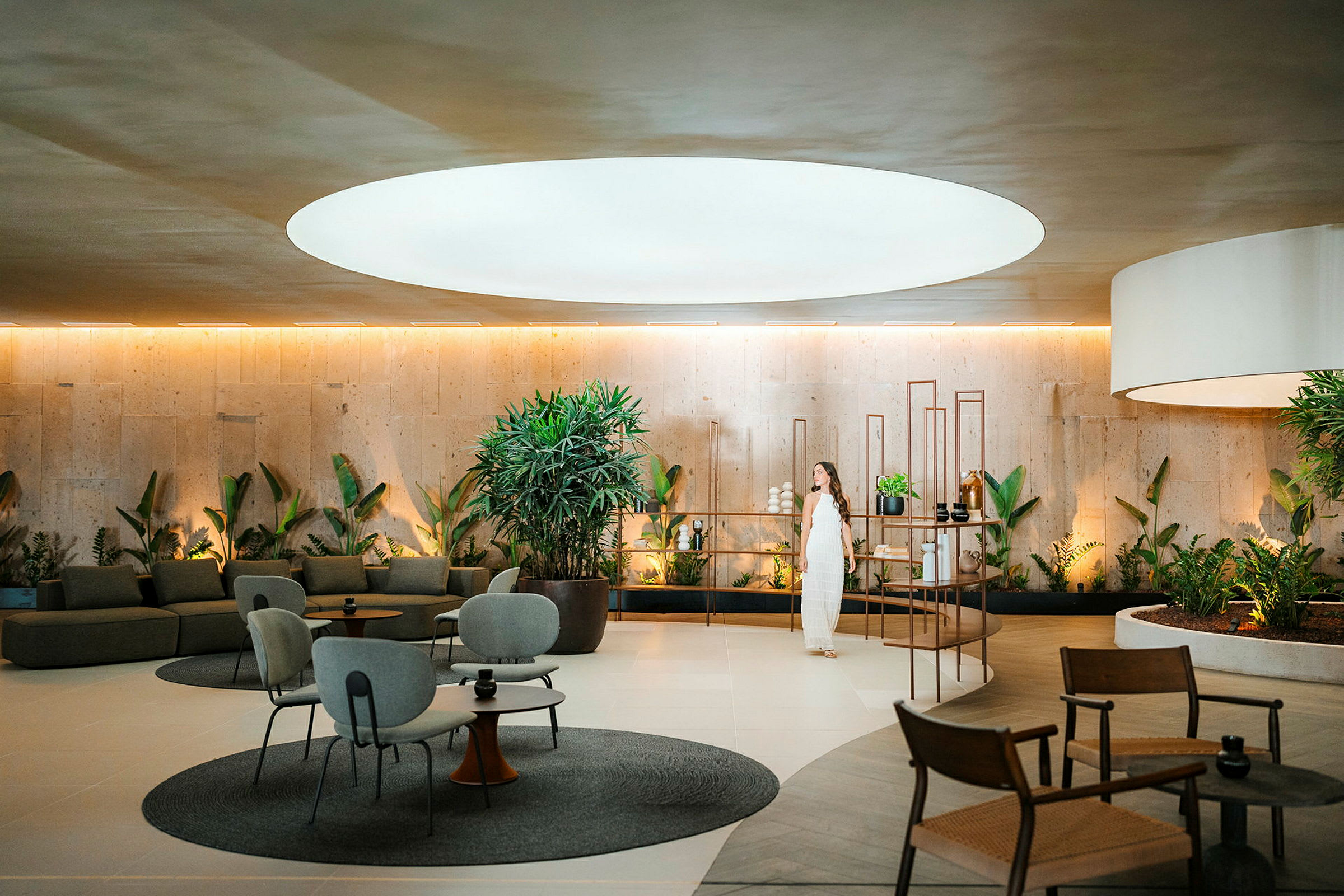 En modern lounge med växter, sittplatser och stor ljusöppning i taket. (AI-genererad text)