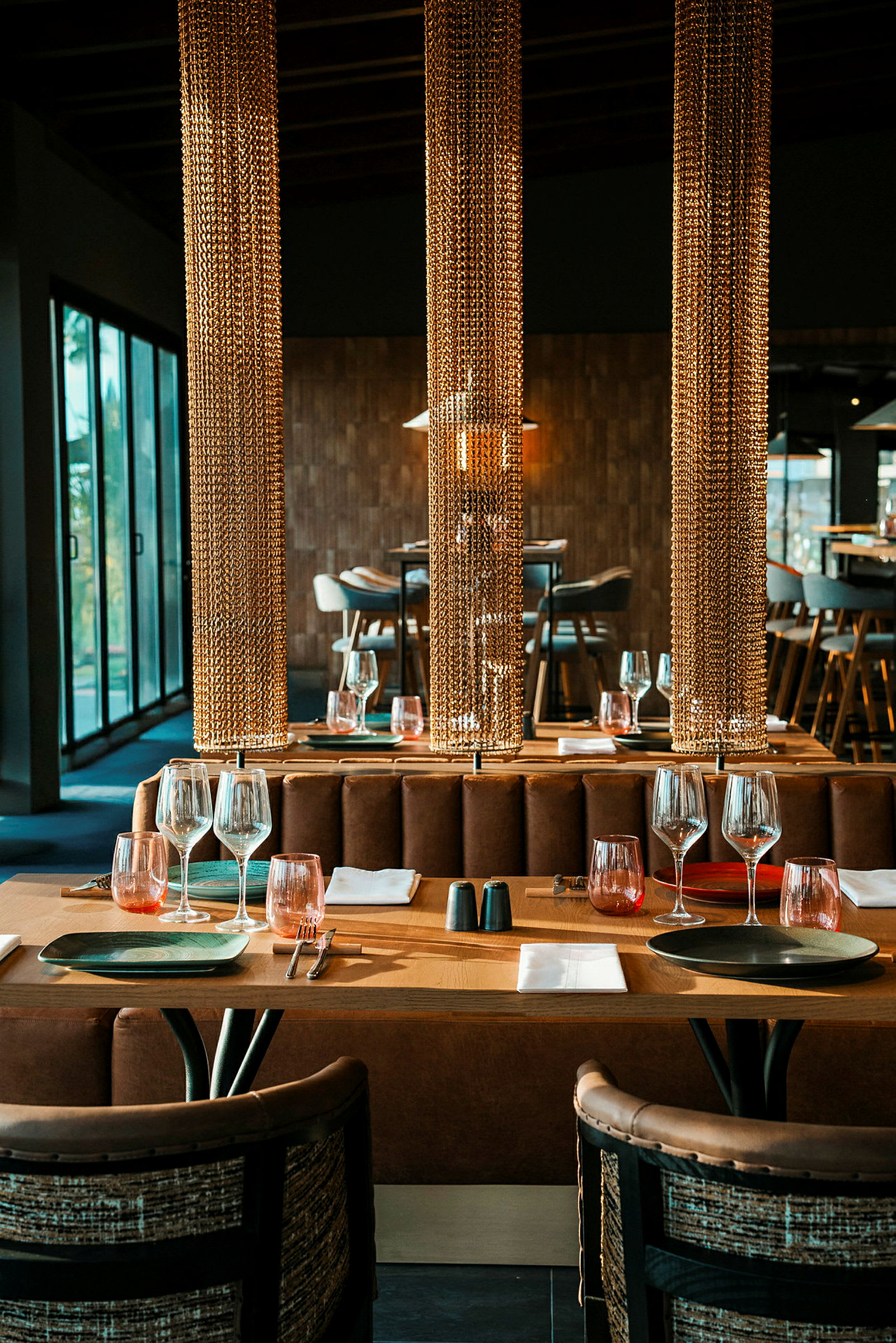 Ett elegant restaurangbord med rustika detaljer, dukat med vinglas och tallrikar, omgivet av dekorativa kedjor. (AI-genererad text)