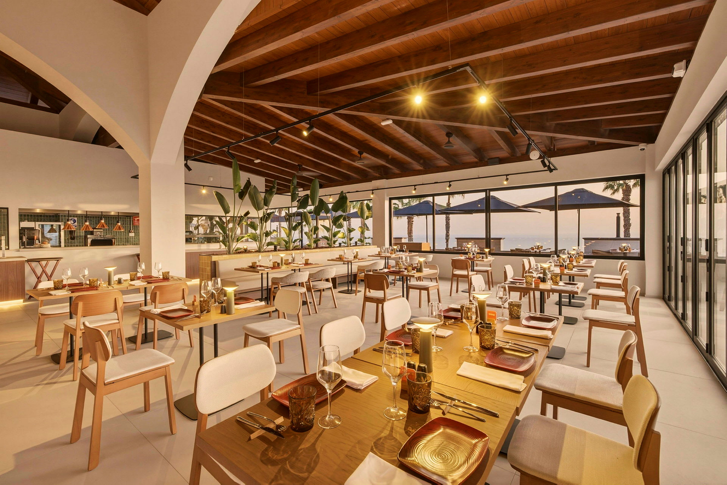 En elegant restaurang med flera sittplatser, stora fönster som vetter mot en utsikt, och en väl upplyst miljö med modern design. (AI-genererad text)