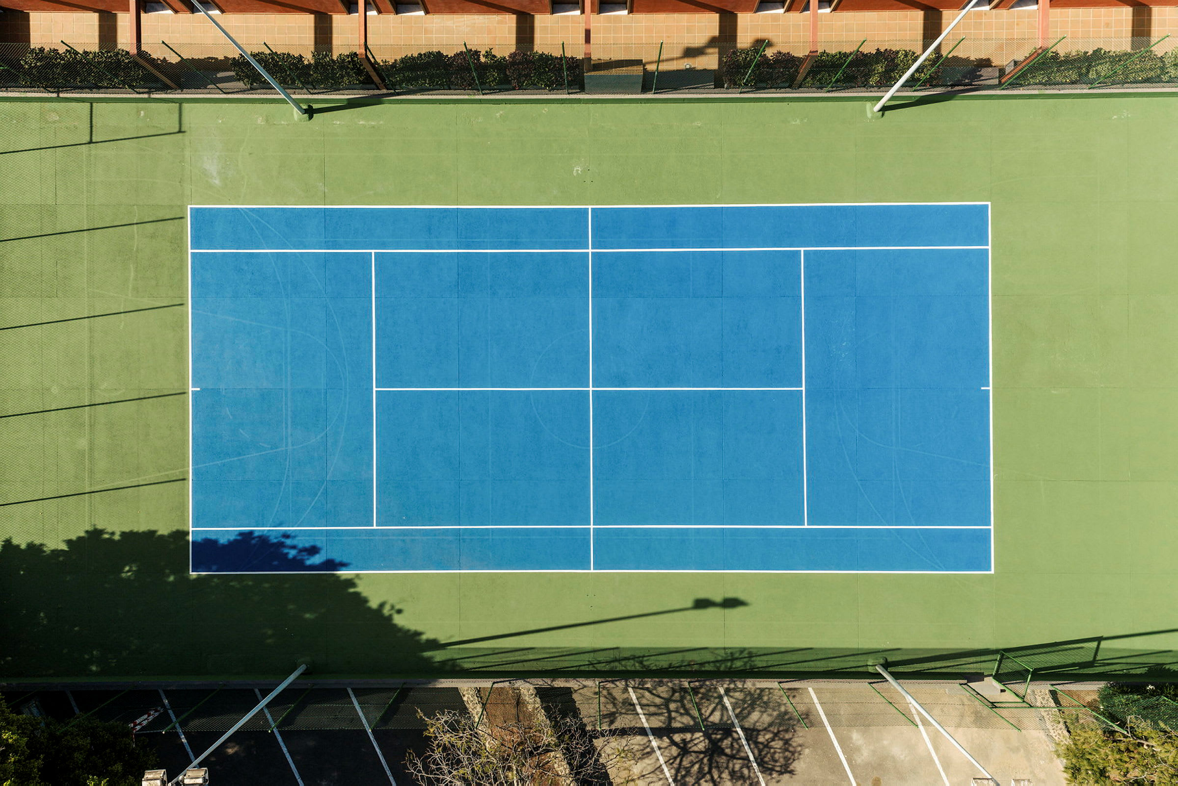 En fågelperspektivbild av en tennisbana med blå plan och gröna kanter. (AI-genererad text)