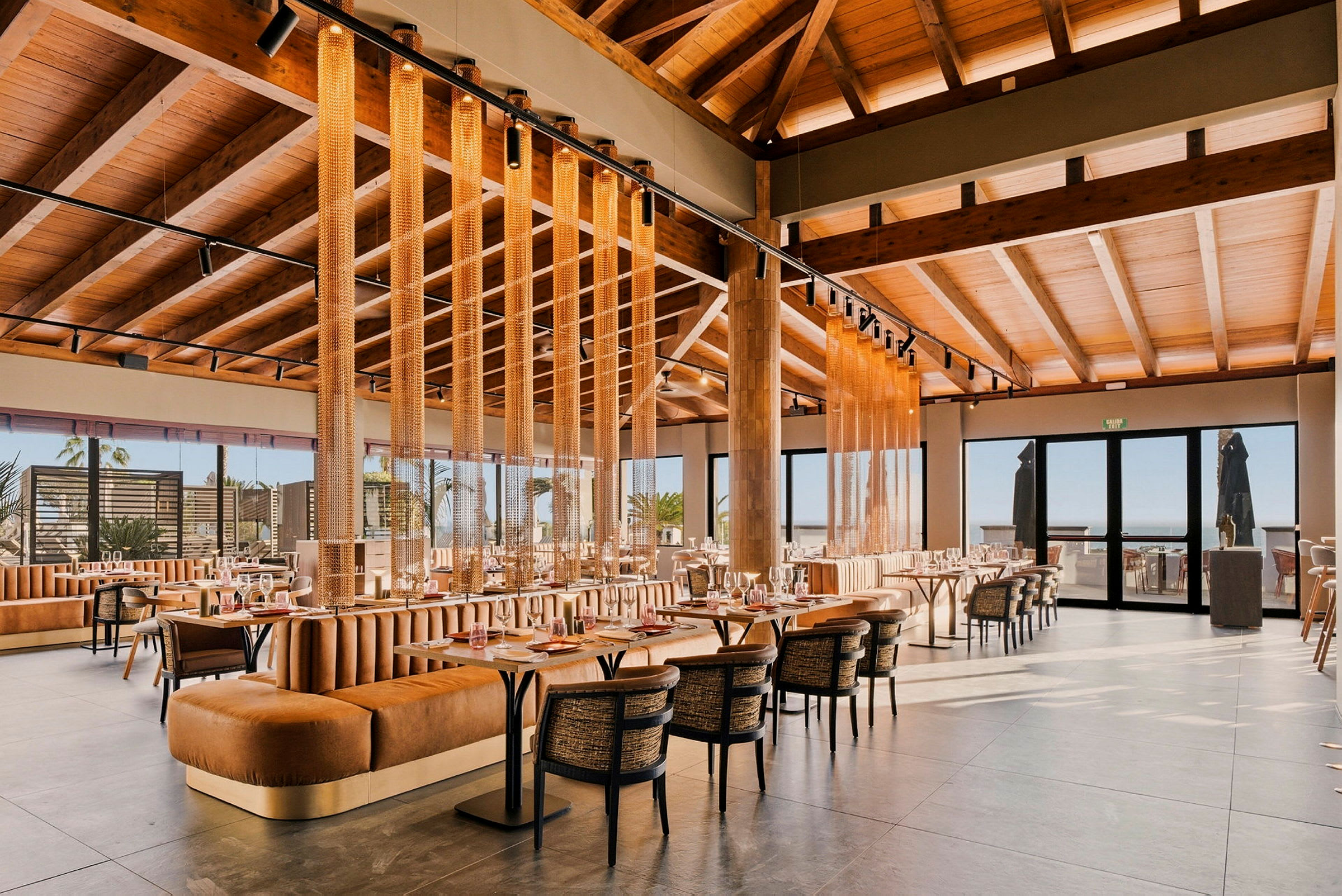 En modern restaurang med träinredning, stora fönster och bekväma sittplatser. (AI-genererad text)