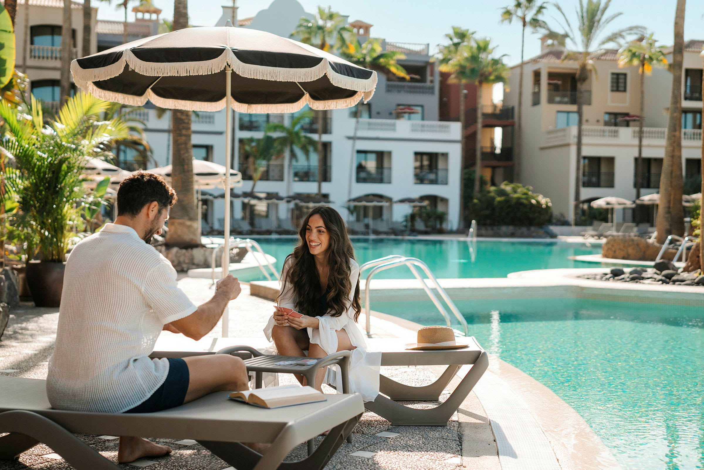 Personer sitter vid en pool under ett parasoll. (AI-genererad text)