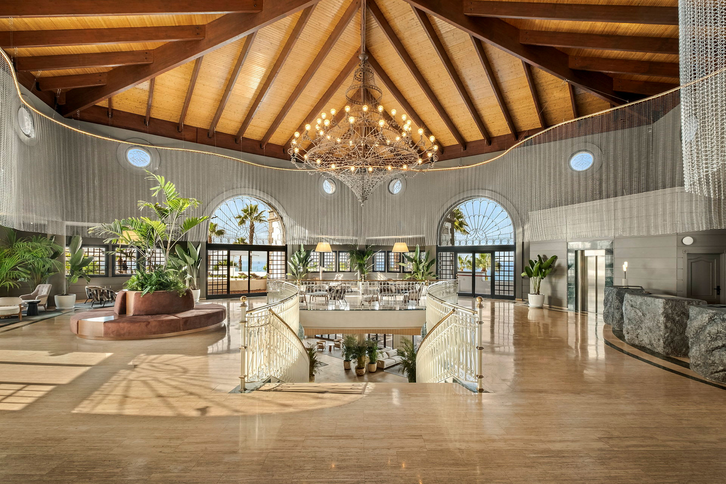 Bild av ett hotelllobbyområde med en stor ljuskrona, moderna möbler och stora fönster. (AI-genererad text)
