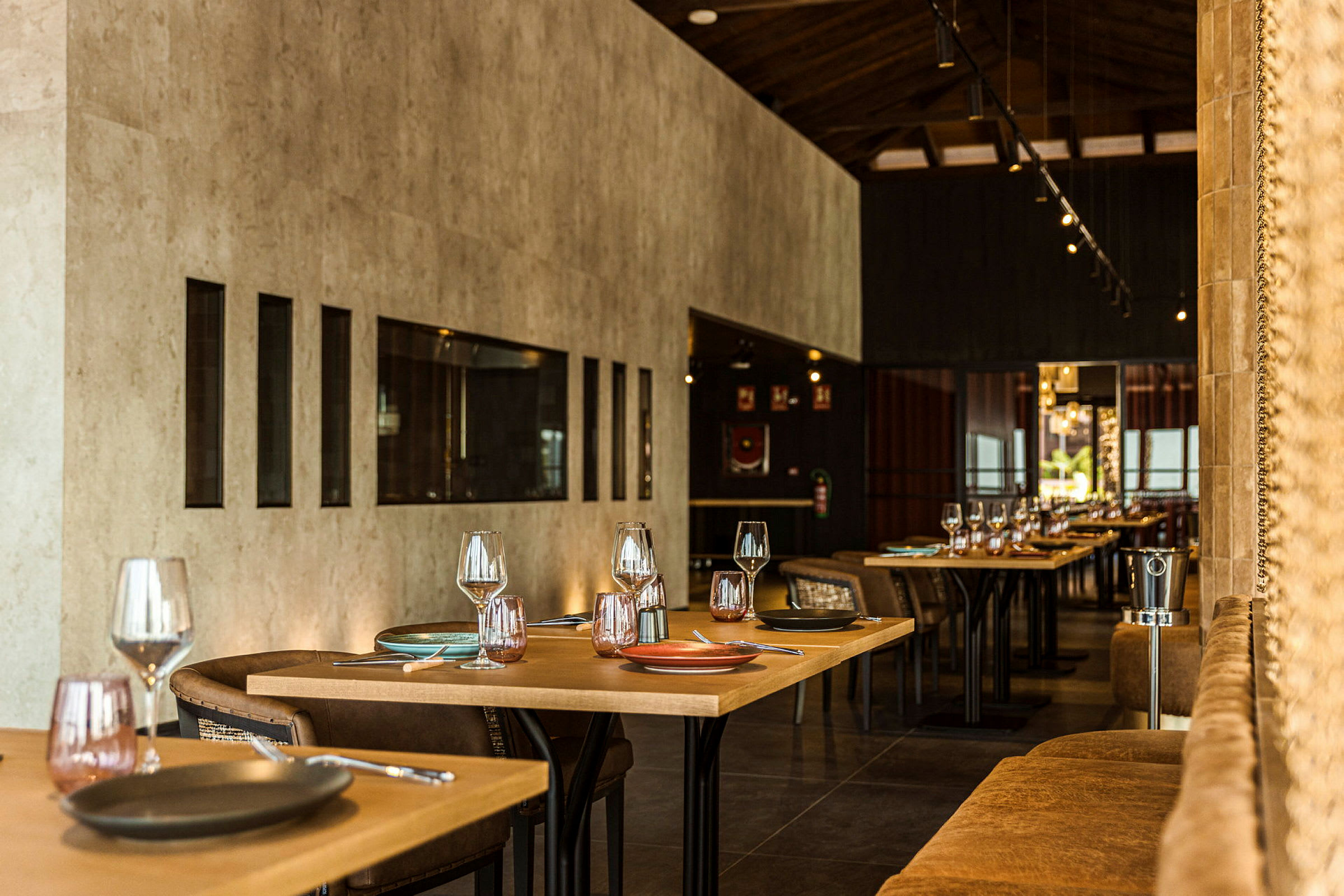 Ett modernt och elegant möblerat restauranginteriör, med dukade bord och stolar arrangerade i en varm atmosfär. (AI-genererad text)