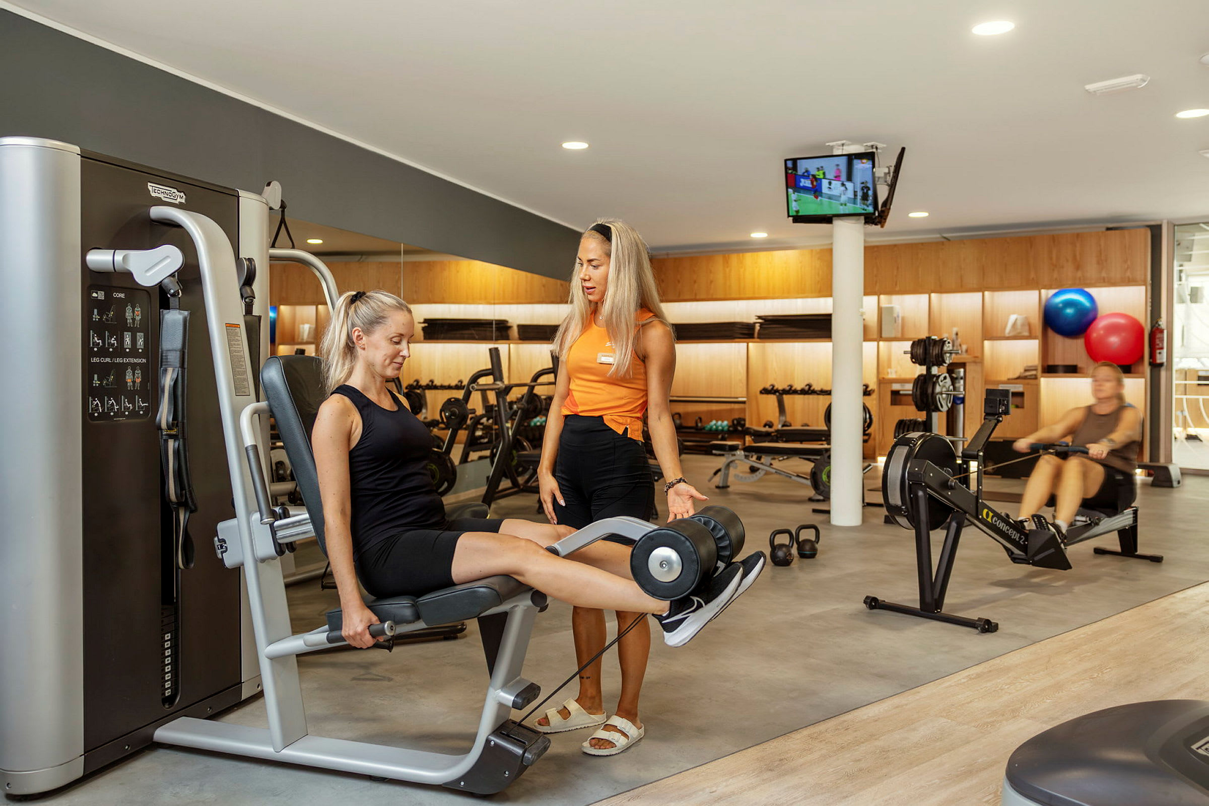 Miljöbild från ett gym med träningsutrustning och personer som tränar. (AI-genererad text)