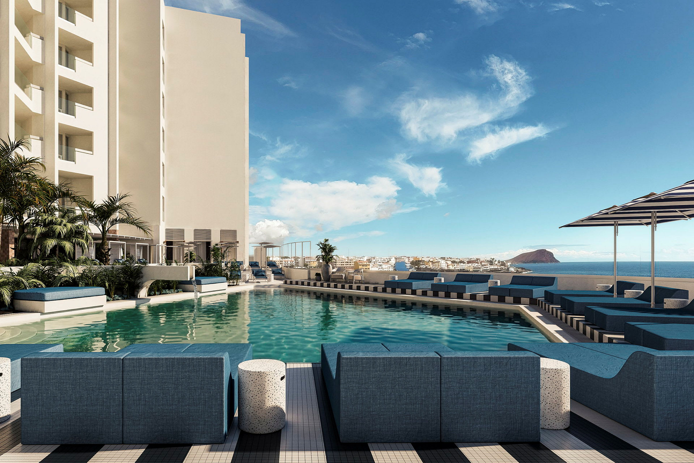 En pool vid ett hotell med solstolar och parasoller, omgiven av byggnader och med utsikt över havet. (AI-genererad text)