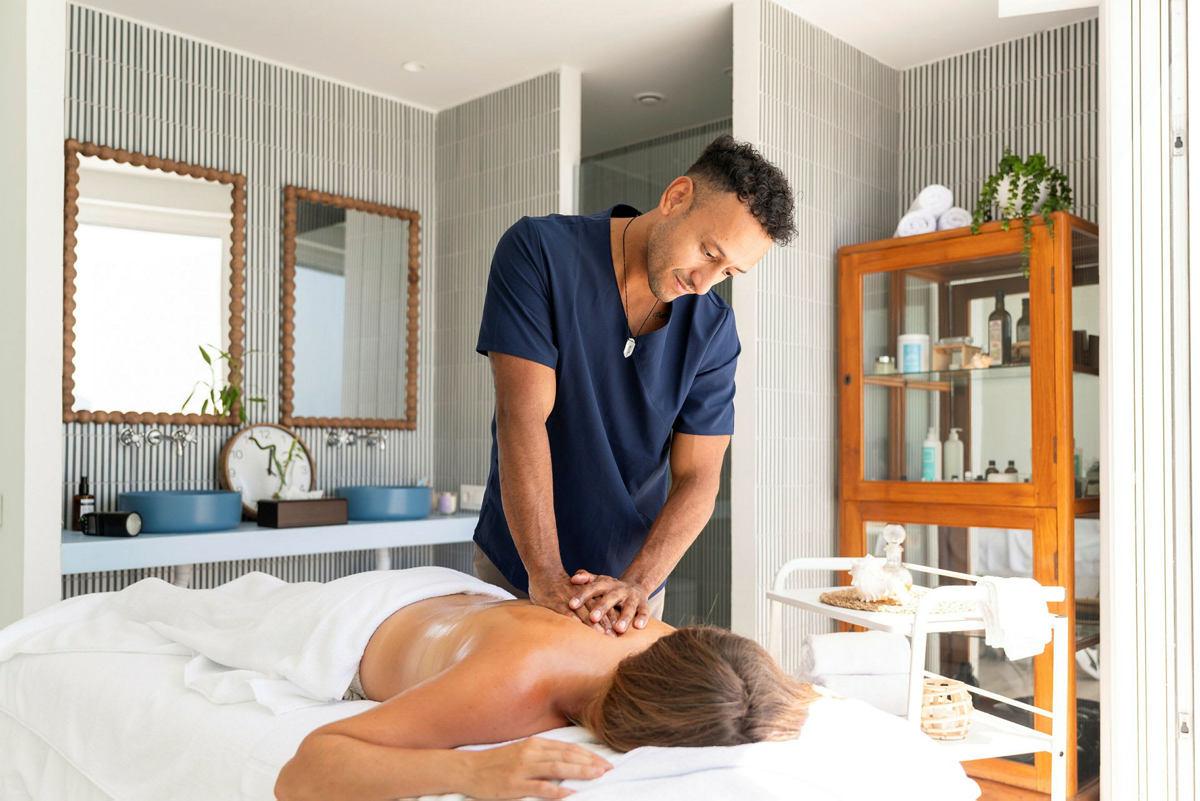 En person får en ryggmassage av en massör i ett ljust och välorganiserat behandlingsrum. (AI-genererad text)
