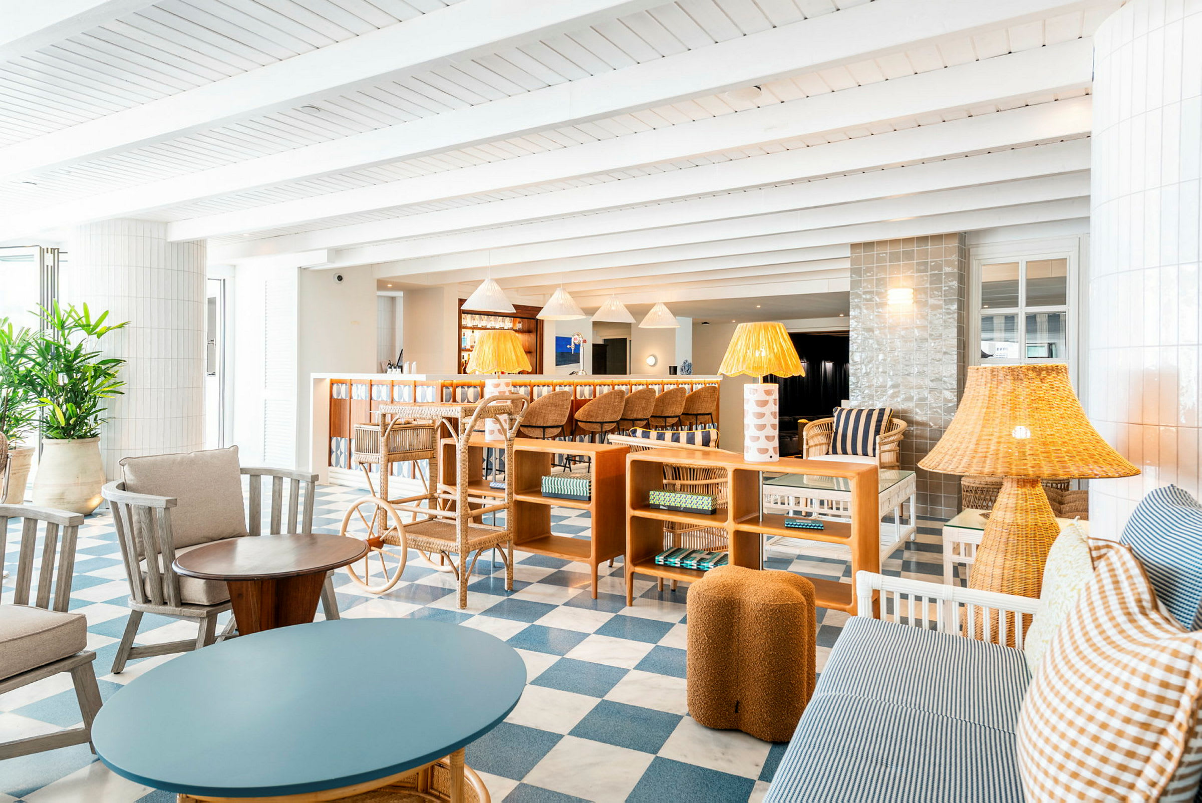 Interiör av en ljus och elegant inredd lounge med soffor, fåtöljer, lampor och ett rutigt golv av blått och vitt. (AI-genererad text)