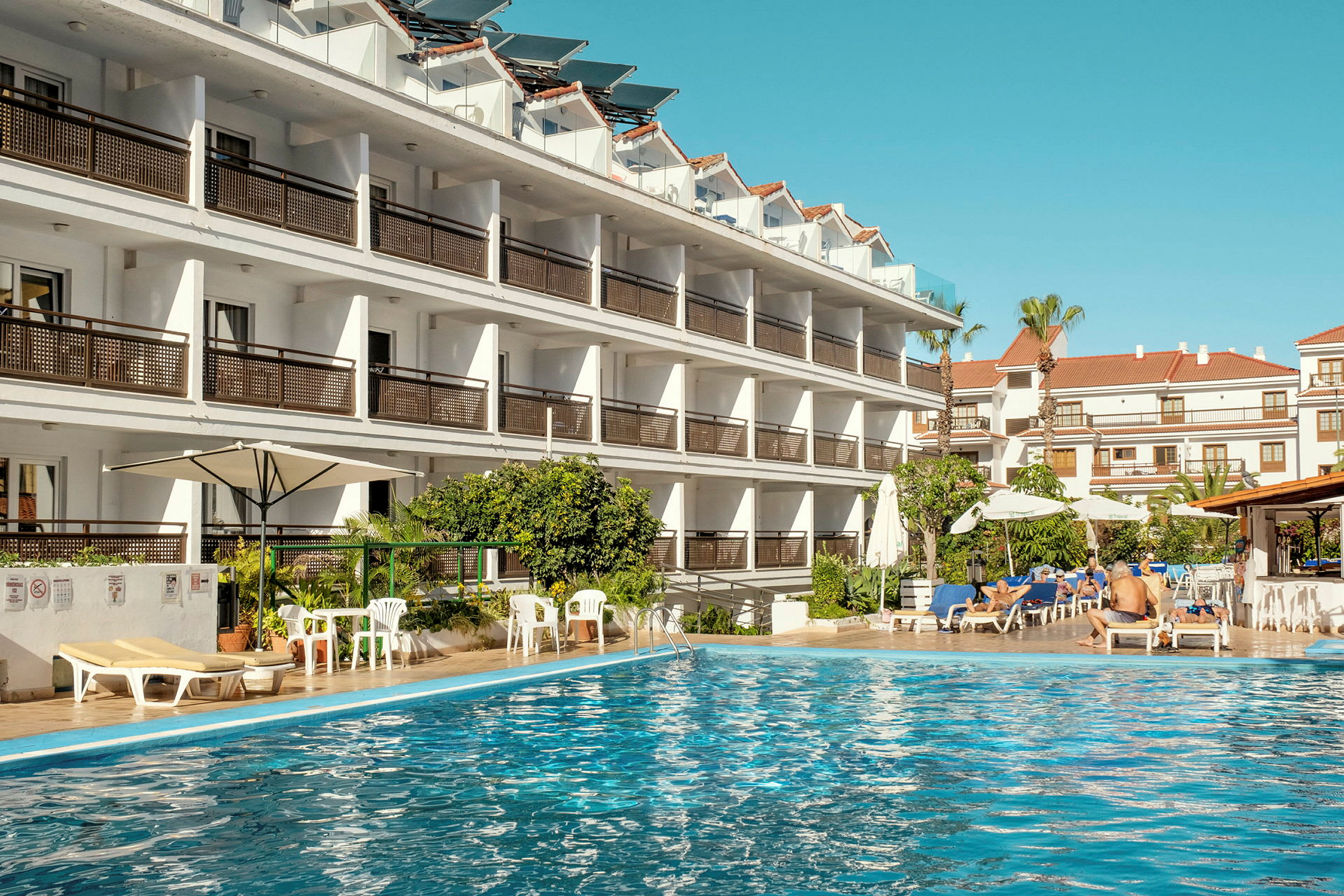 Hotellbyggnad vid en swimmingpool. (AI-genererad text)