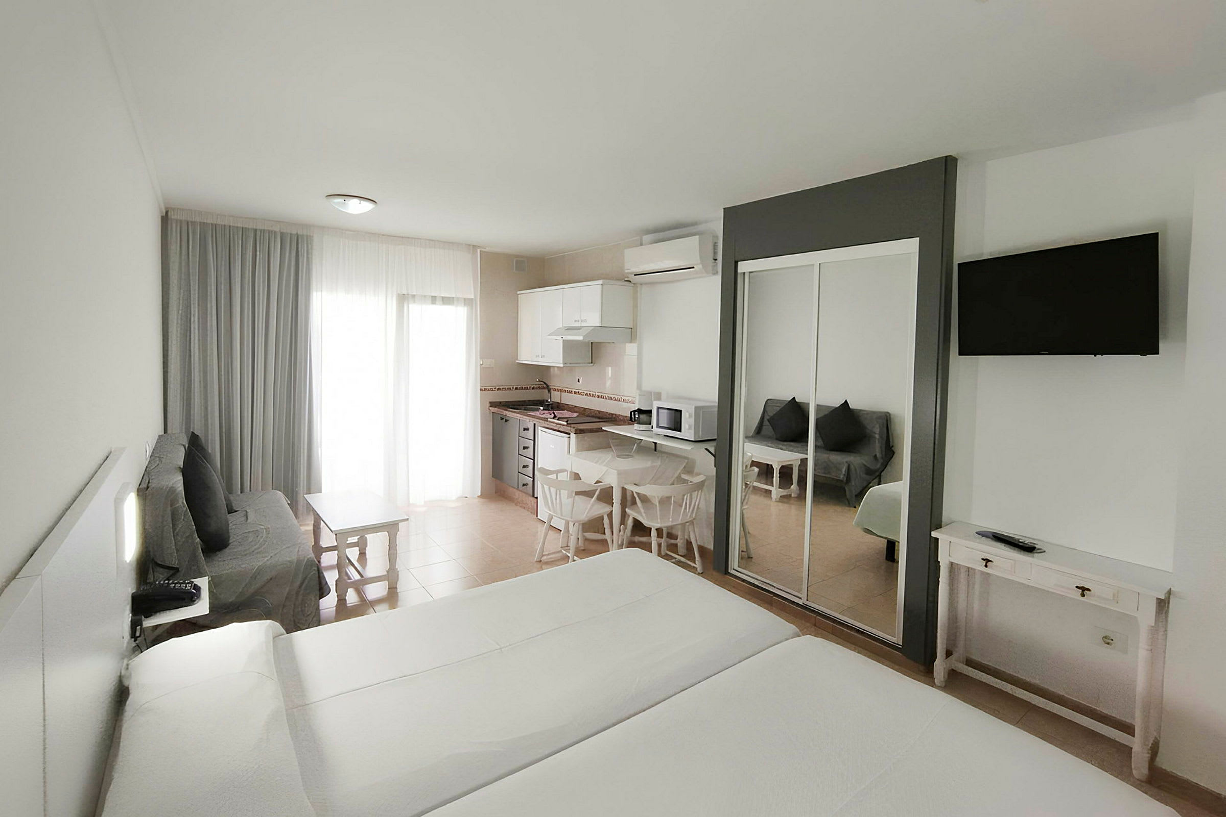 Ett hotellrum med två sängar, en sittgrupp, ett kök och en TV. (AI-genererad text)