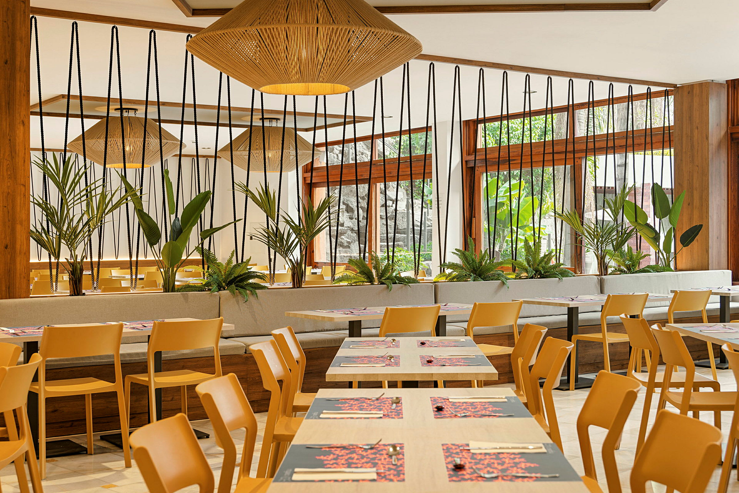Ett modernt inrett restaurangområde med trästolar, bord och gröna växter. (AI-genererad text)