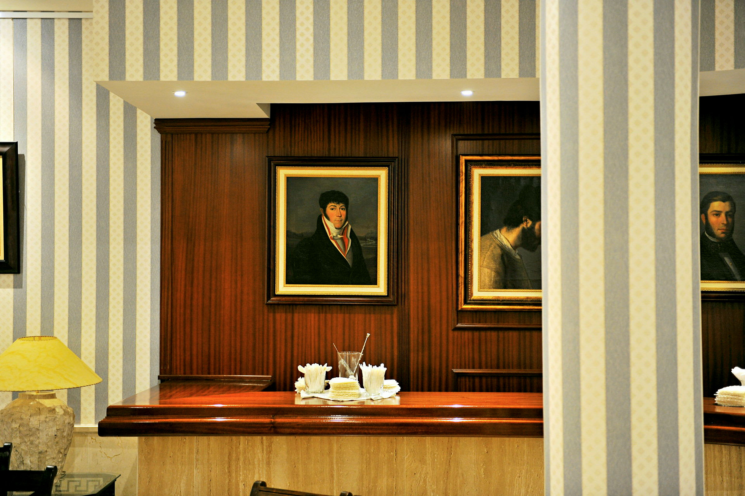Inomhusbild av en reception med träpaneler och tavlor på väggen. Ett bord är dekorerat med servetter och glas. (AI-genererad text)