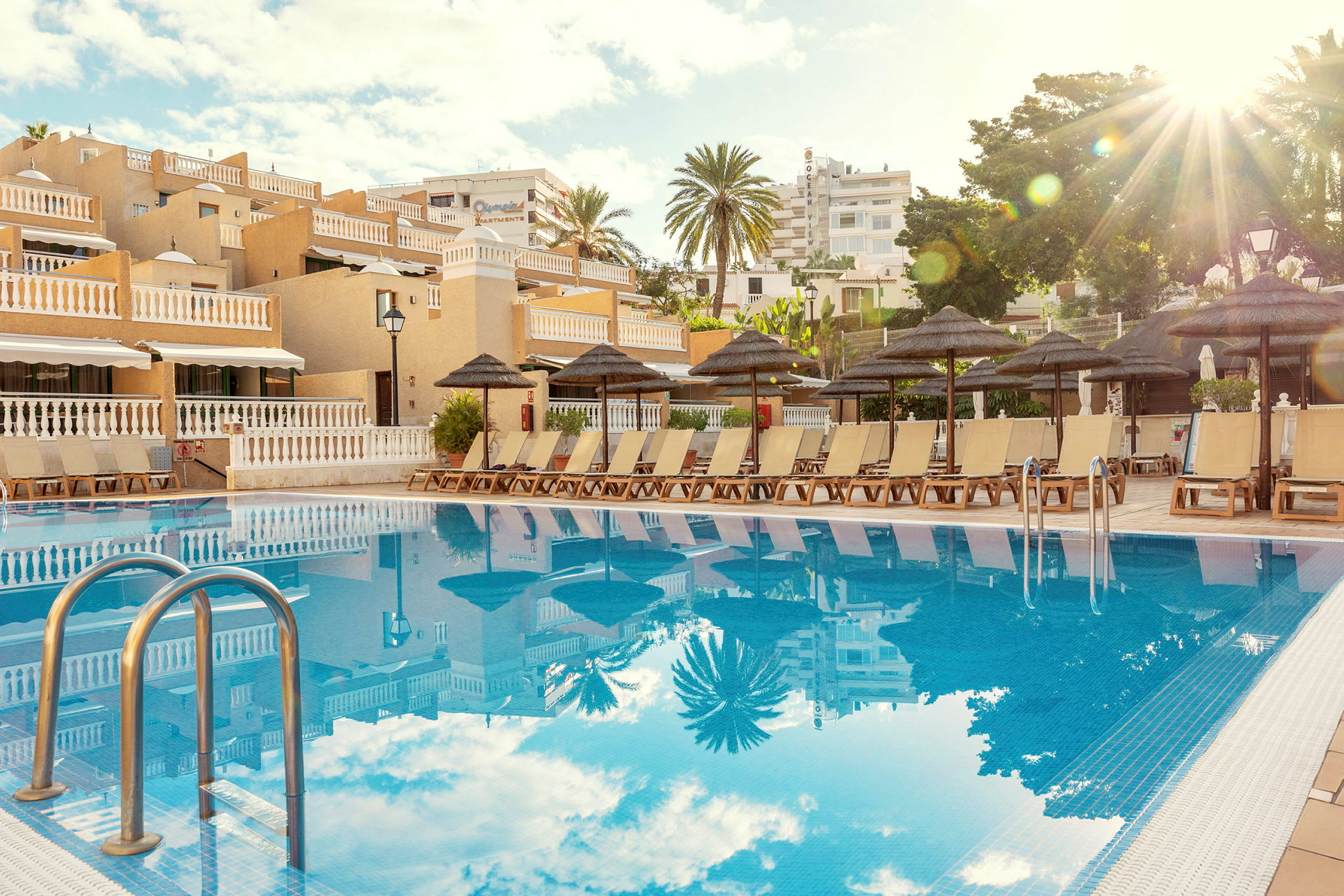 En utomhuspool med solstolar och parasoller vid ett hotell. (AI-genererad text)