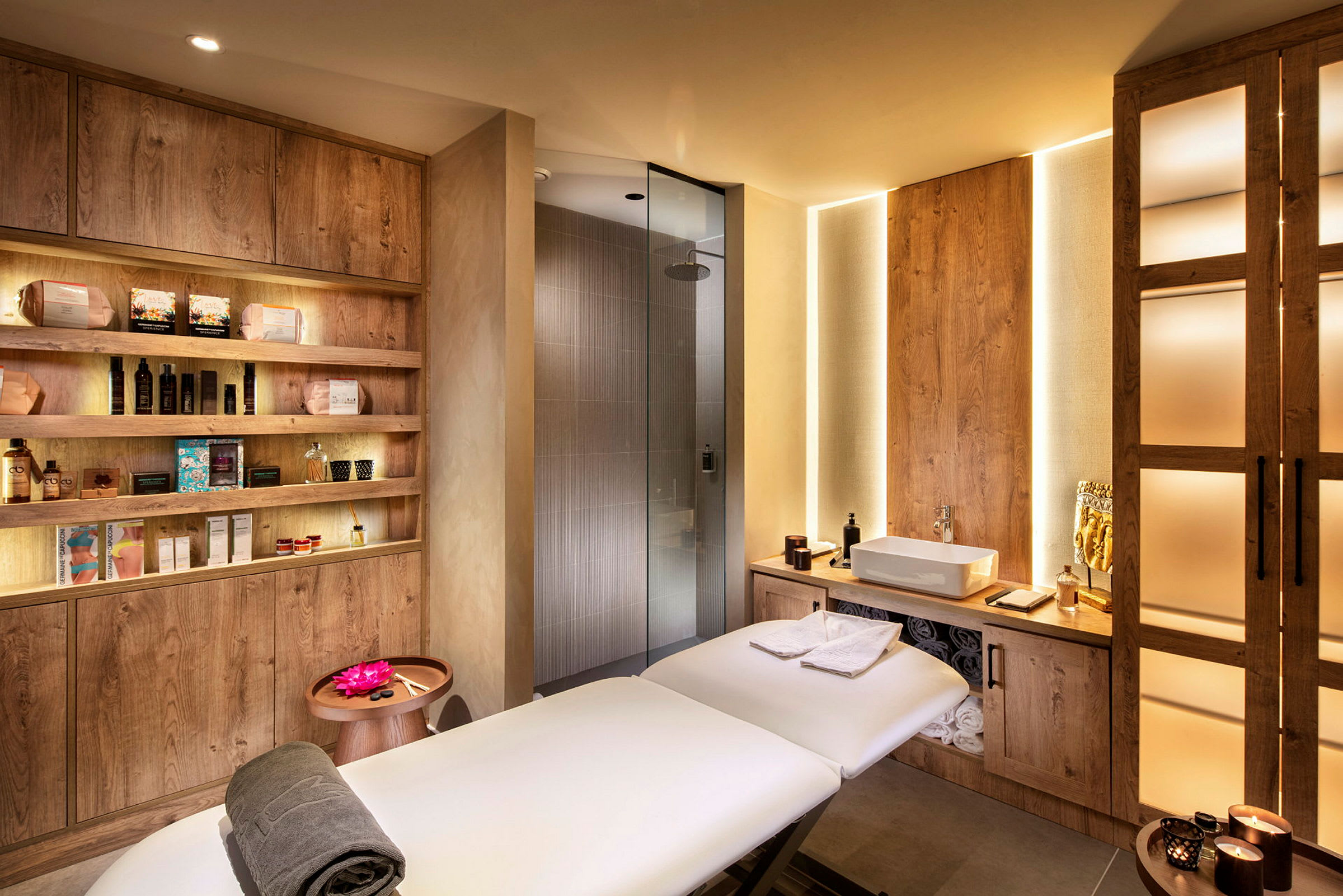 Ett spa rum med massagebänk, handdukar, skönhetsprodukter och en dusch. (AI-genererad text)