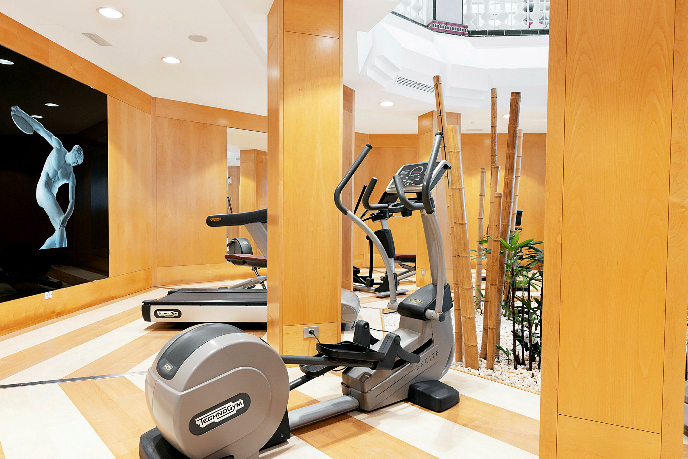 Ett gym med träningsutrustning och dekorativa bambustänger. (AI-genererad text)