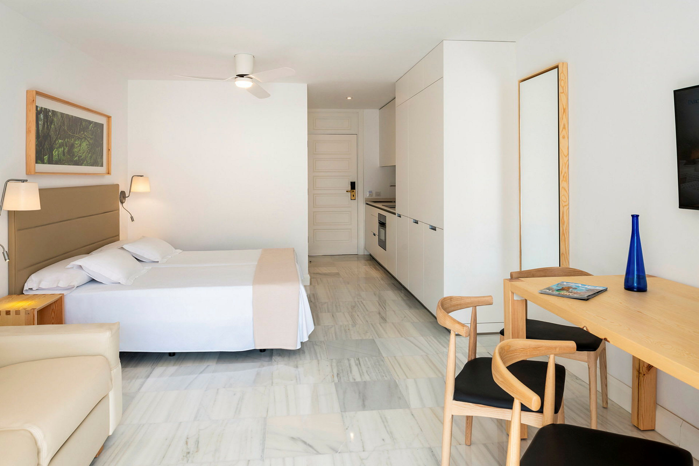 Modernt inrett hotellrum med köksdel och matsalsbord. (AI-genererad text)