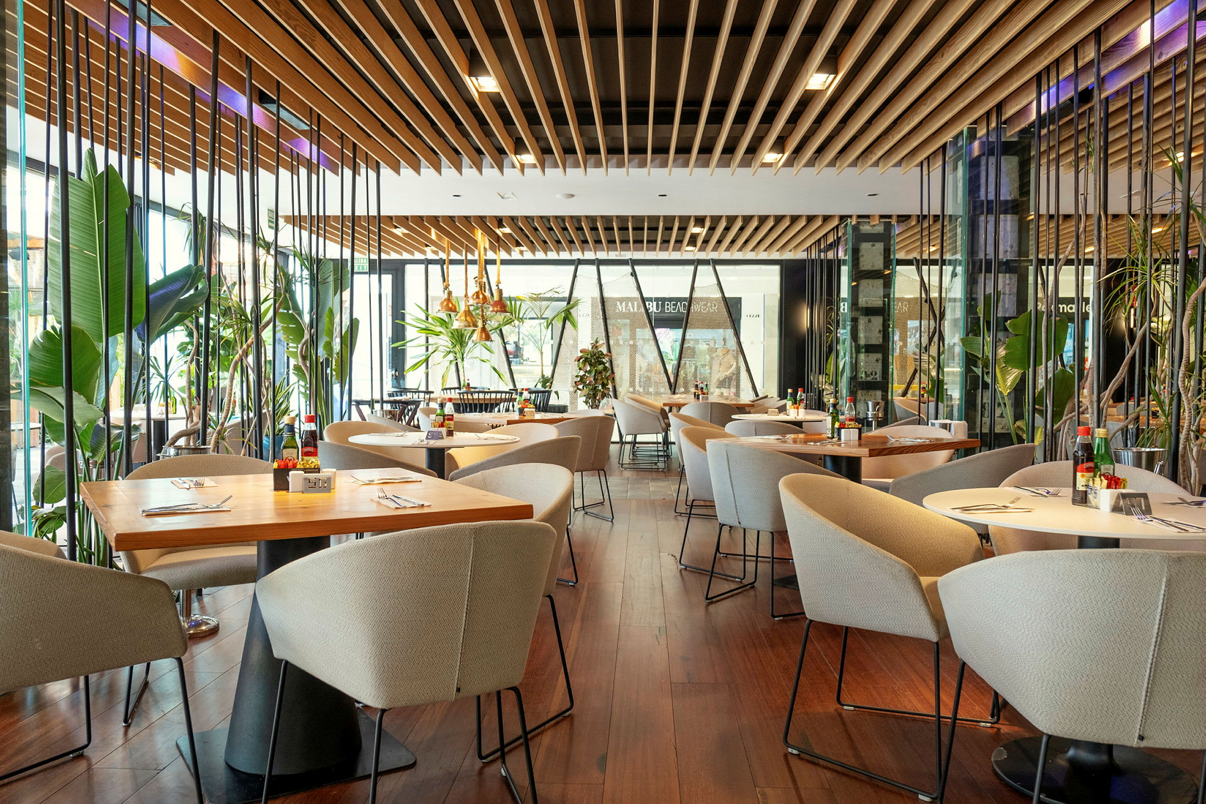 Modern restaurang med bord, stolar och grönskande växter. (AI-genererad text)